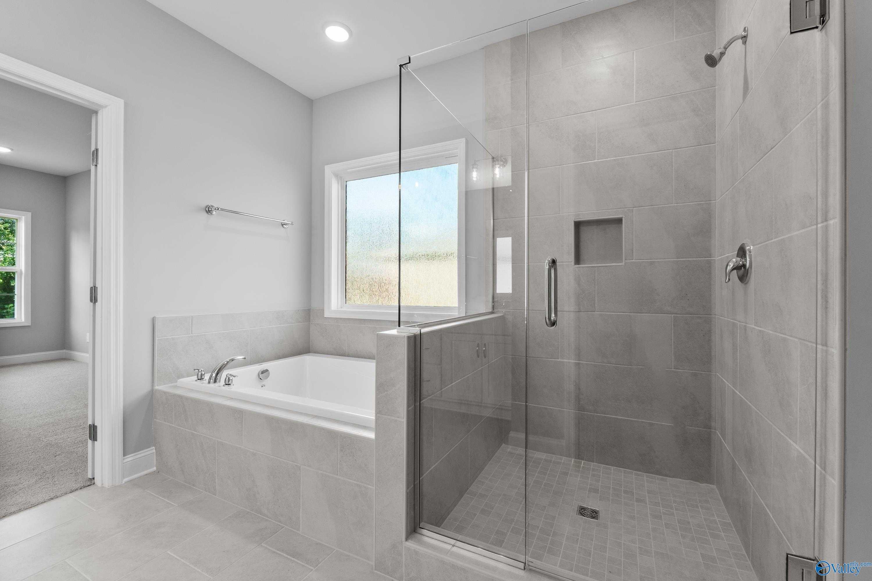 Modern master bathroom with gray subway tile, frameless glass shower, and soaking tub in Davidson Homes The Rockford, Harvest, AL