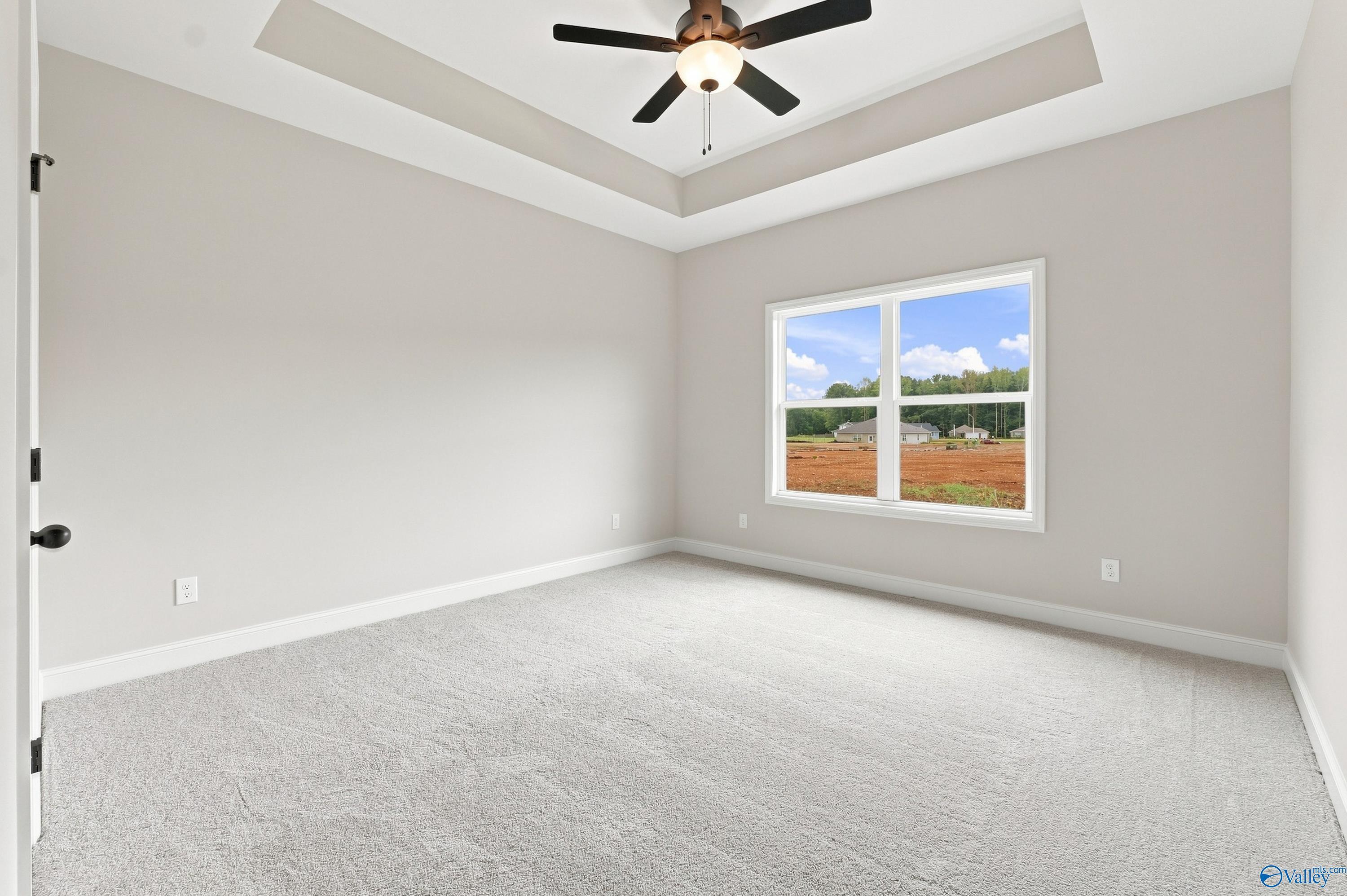 Bright bedroom with tray ceiling and ceiling fan in The Asheville E floor plan at Forest Glen, Hazel Green, Alabama.