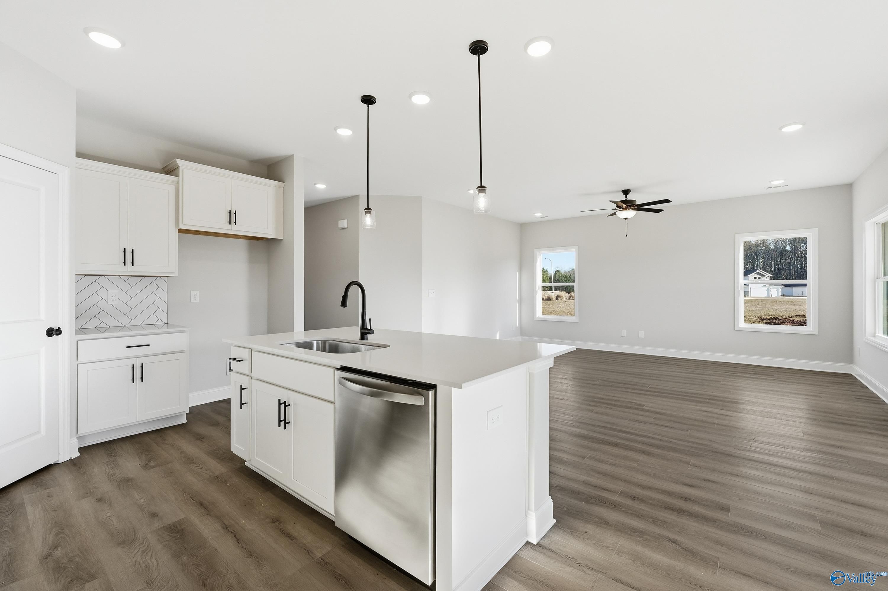 Modern white kitchen with island sink, stainless dishwasher, subway backsplash, and open living in Franklin E home, Hazel Green, AL
