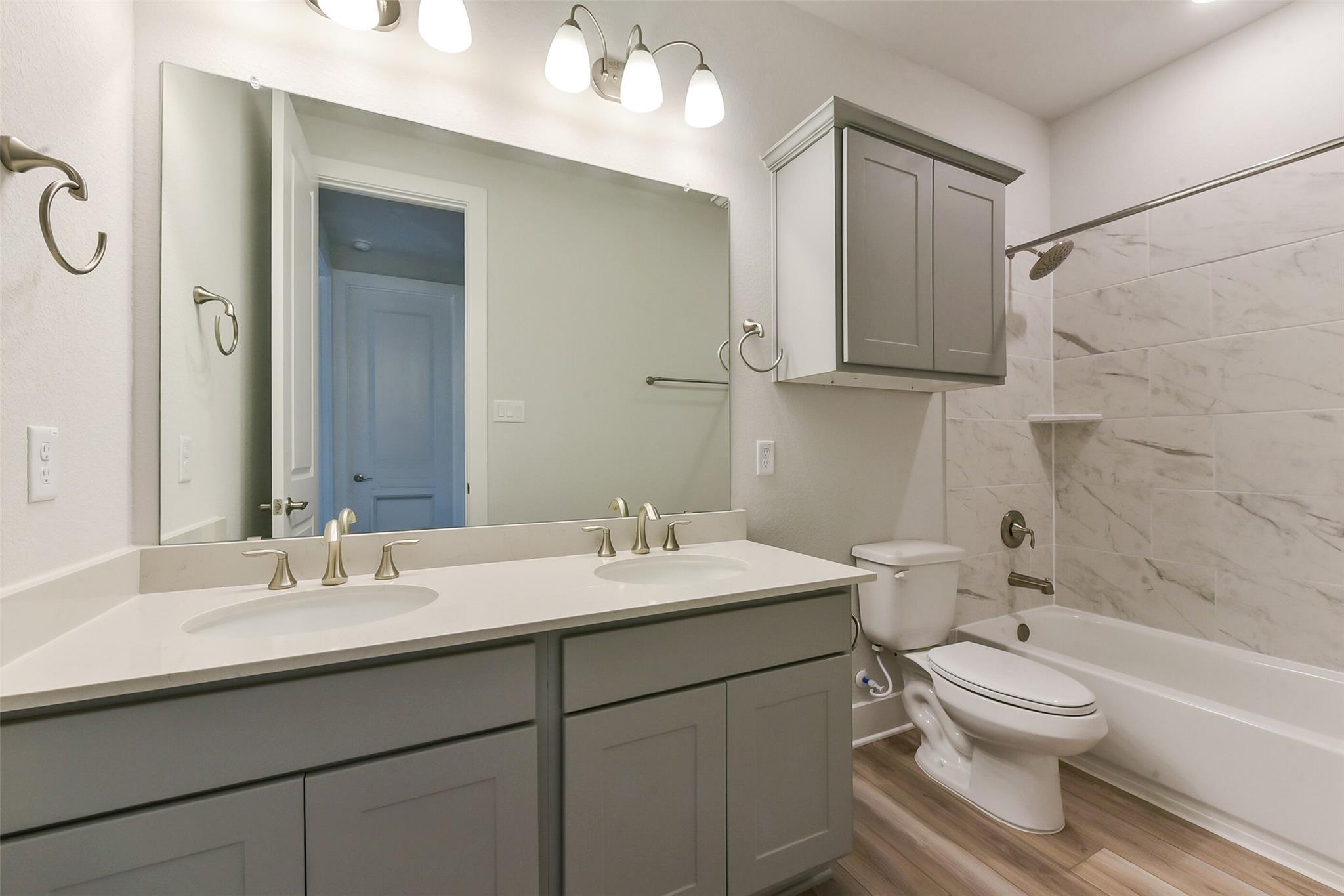 Modern master bathroom with double vanity, gray cabinets, subway tile shower, tub in Davidson Homes The Edward A, Texas City, Texas