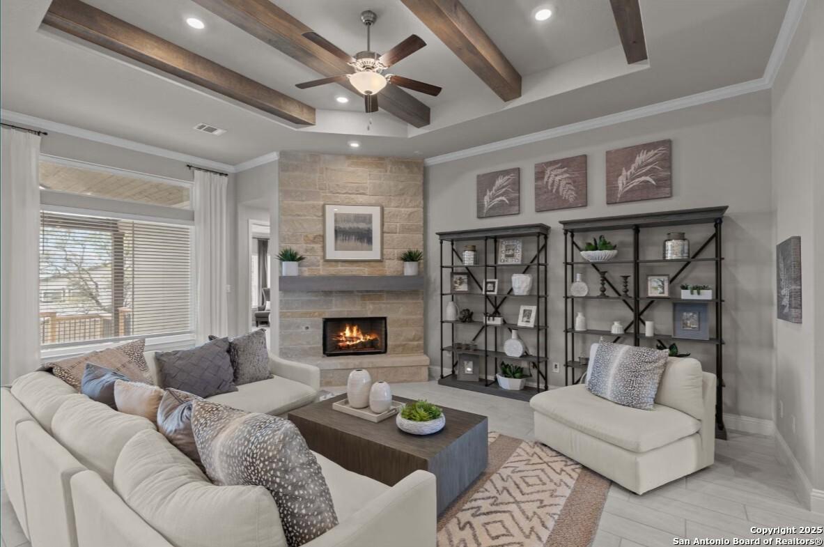 Cozy living room with stone fireplace, exposed beam ceiling, and neutral sofa in Davidson Homes The Garner B, Ladera, San Antonio