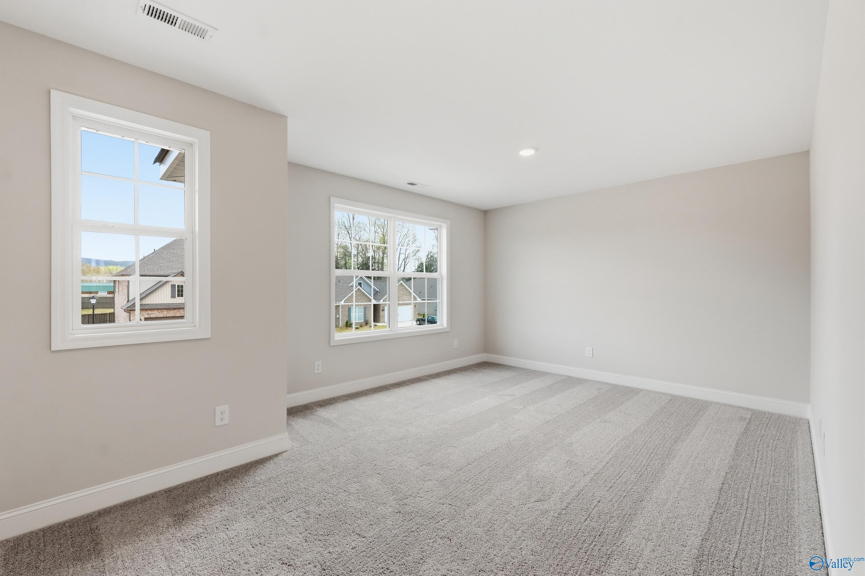 Bright empty bedroom with neutral gray walls, double windows, and plush carpet in Davidson Homes Shelby B, New Market, Alabama