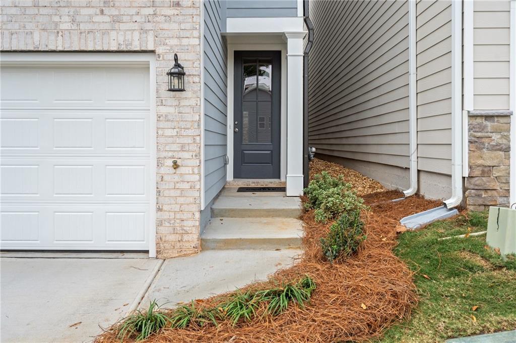 Two-car garage with brick accents and dark entry door on modern siding facade of Davidson Homes The Cary A in Kennesaw, Georgia