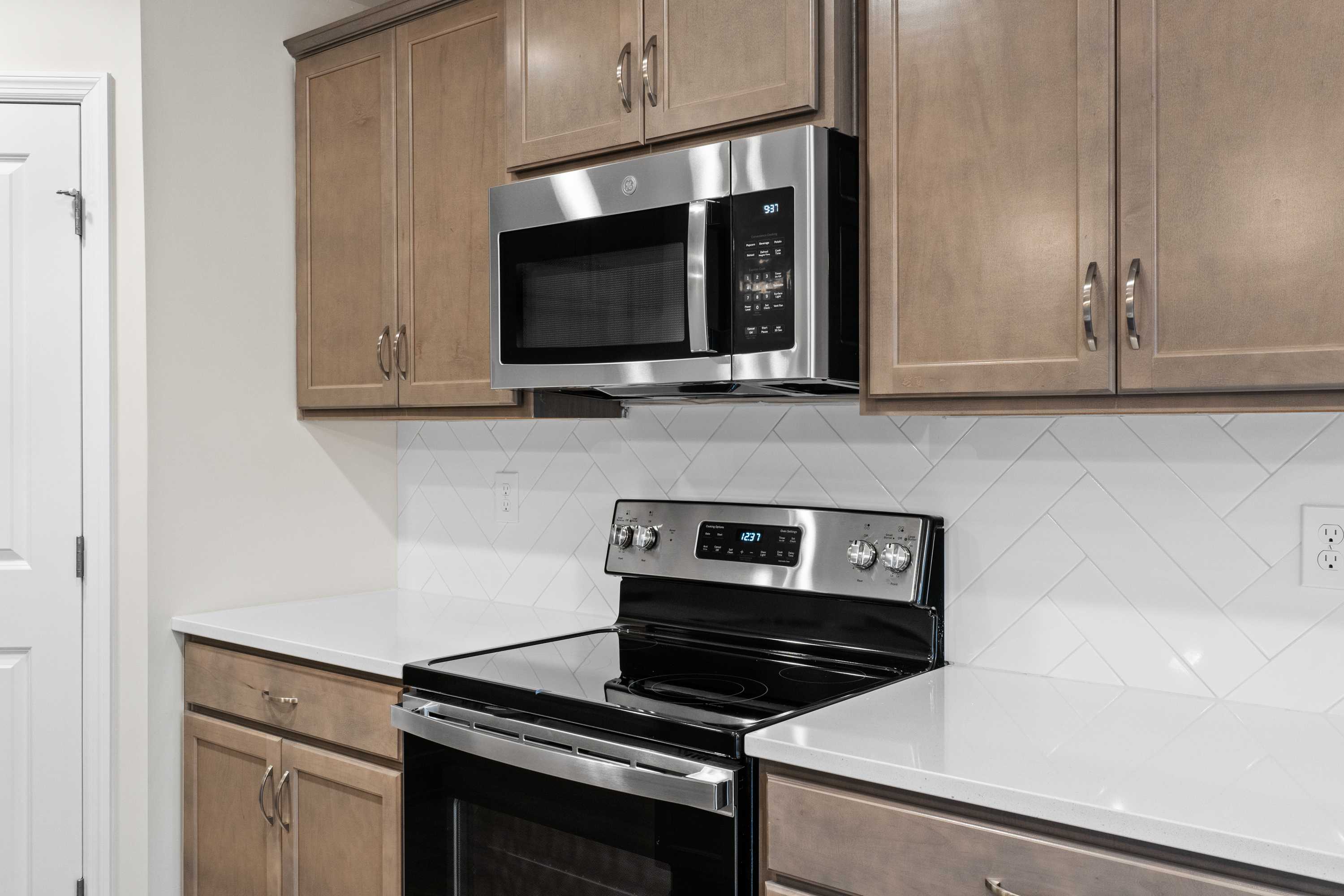 Modern kitchen in The Asheville by Davidson Homes featuring white quartz counters, subway tile backsplash, and stainless steel appliances