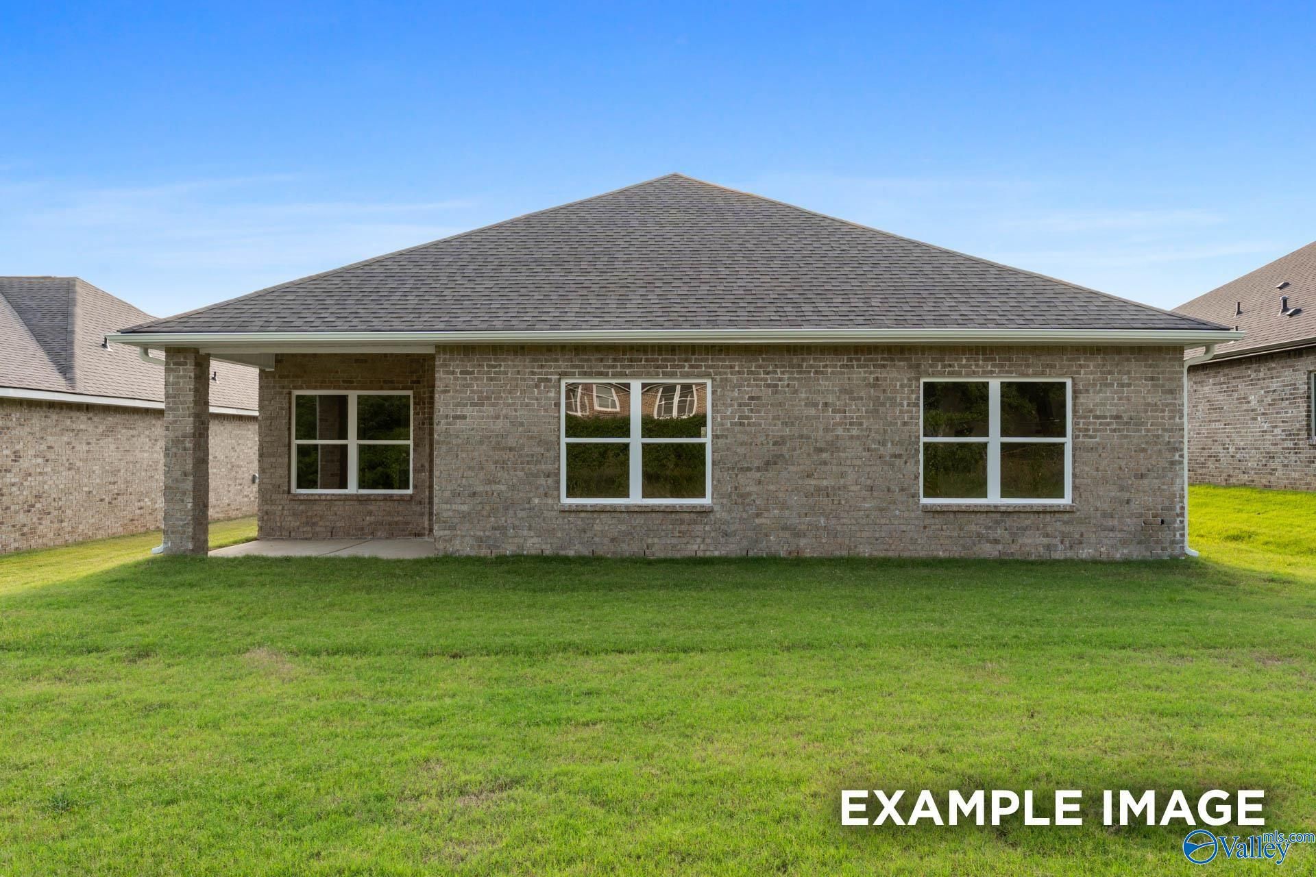 Back view of single-story brick Daphne C home with gabled roof, large windows, covered porch, and lush green lawn in Ivy Hills, Toney, Alabama
