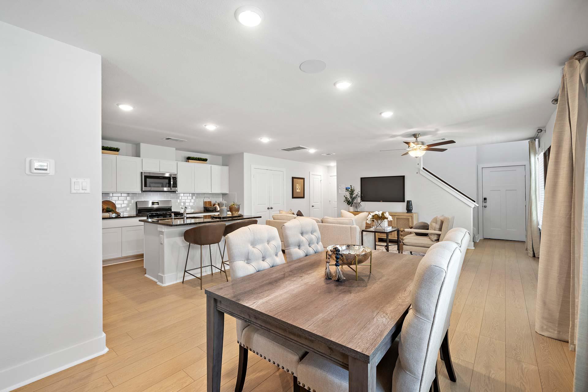 Open-concept kitchen and dining area at Haven at Kieth Harrow in Cypress Texas with white cabinets, island, and hardwood floors