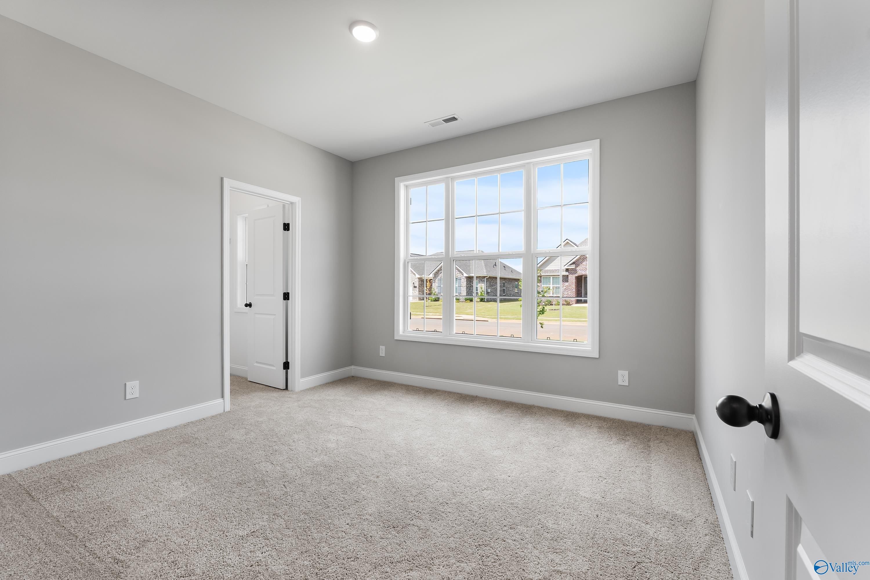 Bright secondary bedroom with gray walls, carpet flooring, and large window overlooking neighborhood in Davidson Homes The Montgomery B With Bonus, Toney, Alabama