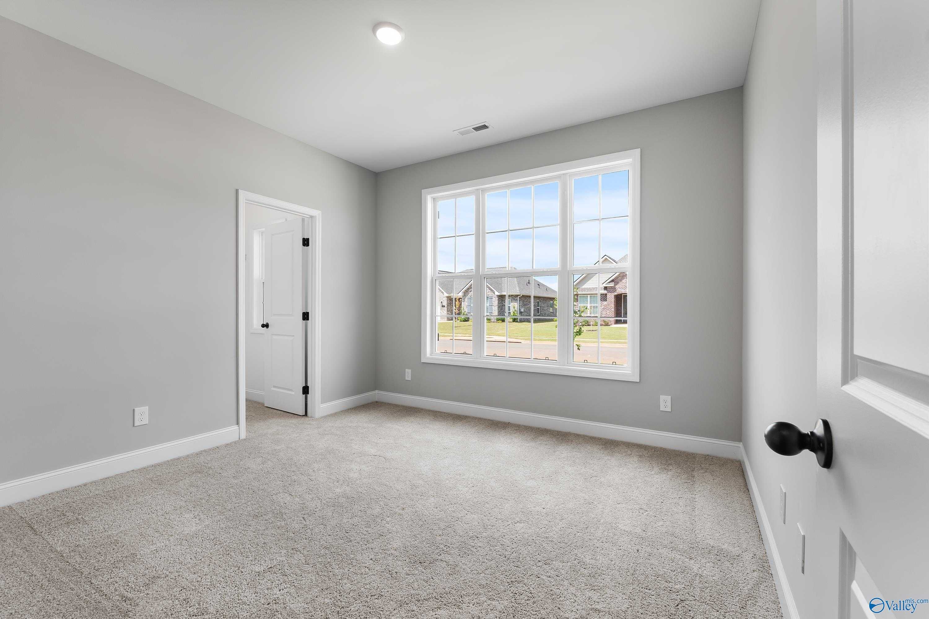 Bright secondary bedroom with gray walls, carpet flooring, and large window view in Davidson Homes Montgomery B, Toney, AL