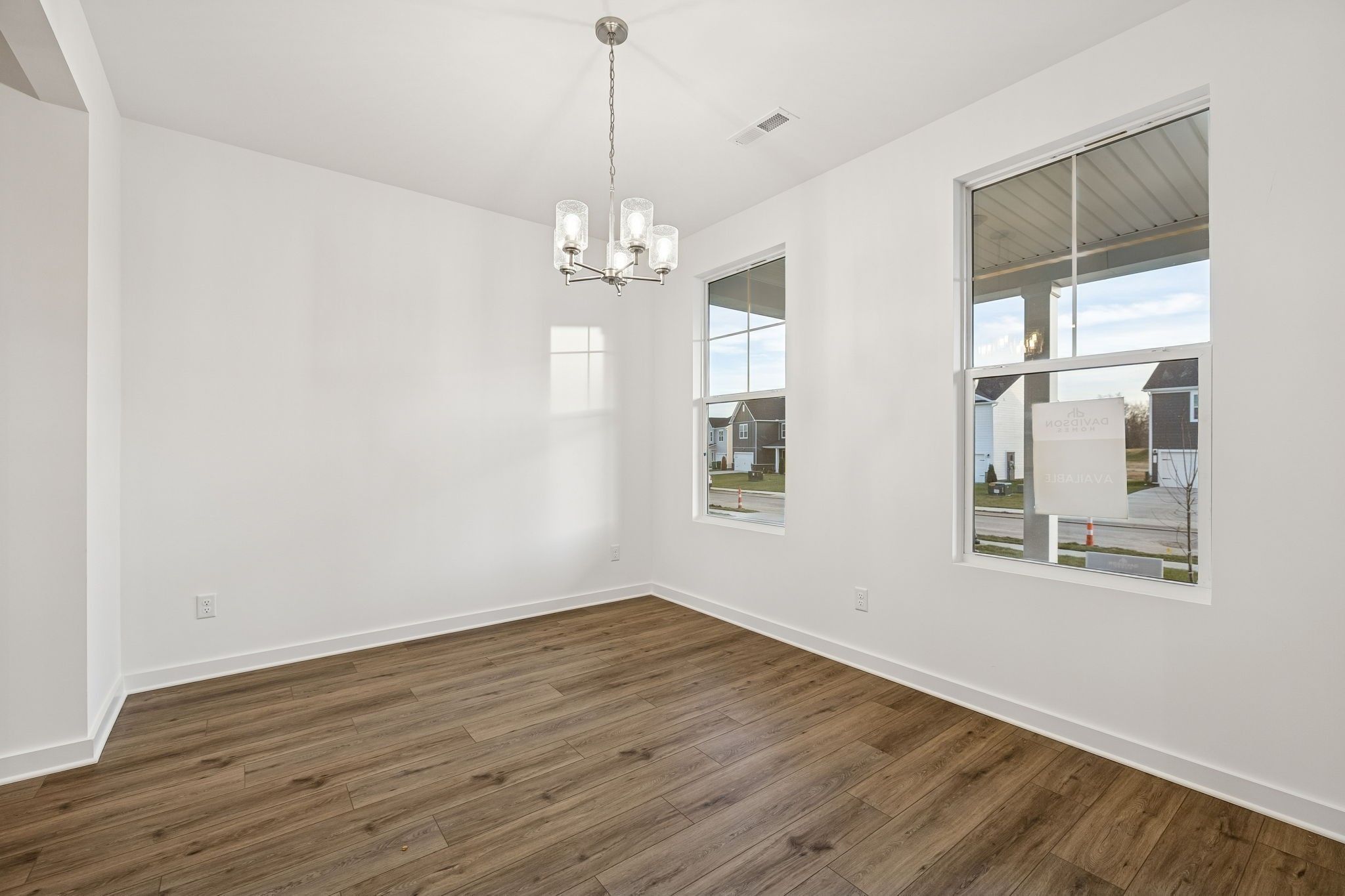 Bright dining area with wood-look flooring and modern chandelier in The Willow B floor plan, Calista Farms, White House, TN.