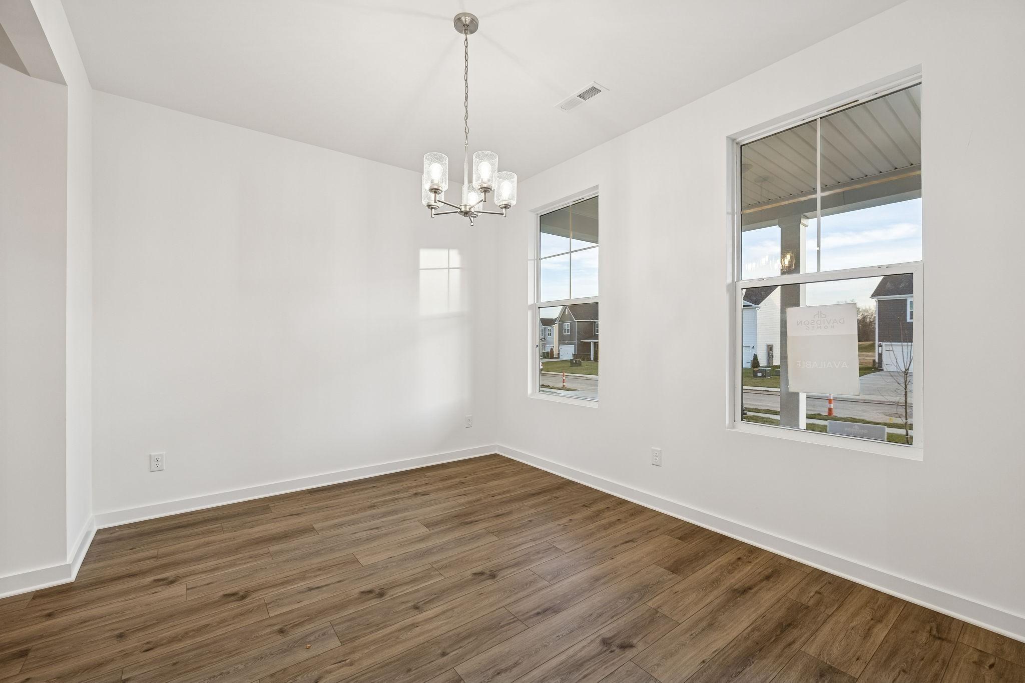 Bright dining area with wood-look flooring and modern chandelier in The Willow B floor plan, Calista Farms, White House, TN.