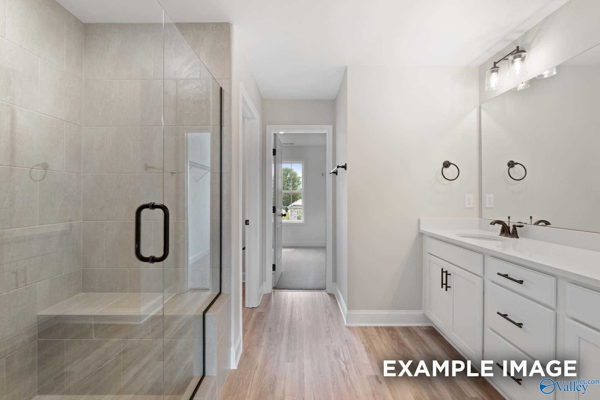 Modern master bathroom with frameless glass shower, double vanity, and hardwood floors in Davidson Homes Shelby A, Athens AL