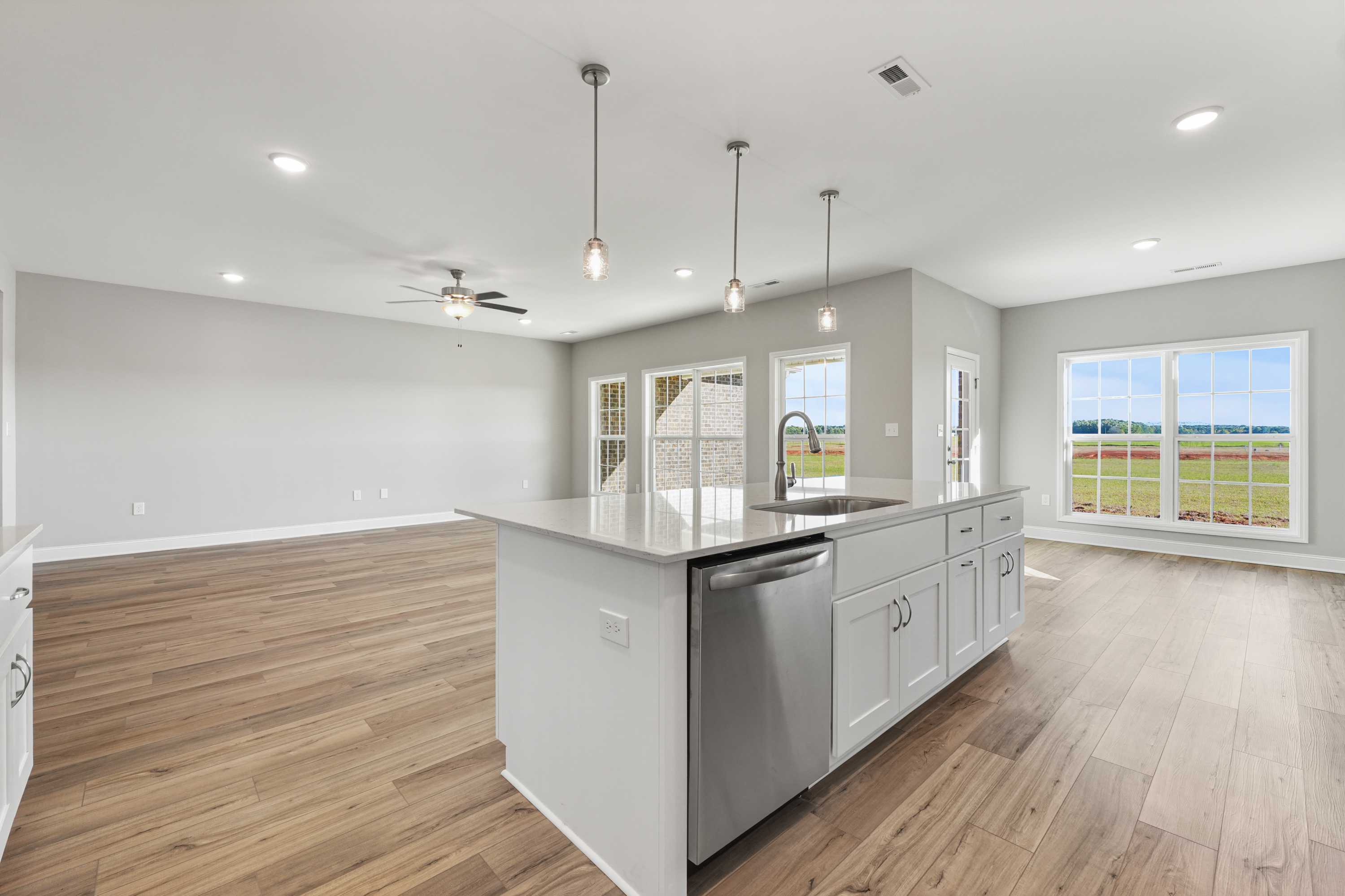 Open-concept kitchen in The Valencia home design featuring white island, stainless appliances, hardwood floors, and scenic window views