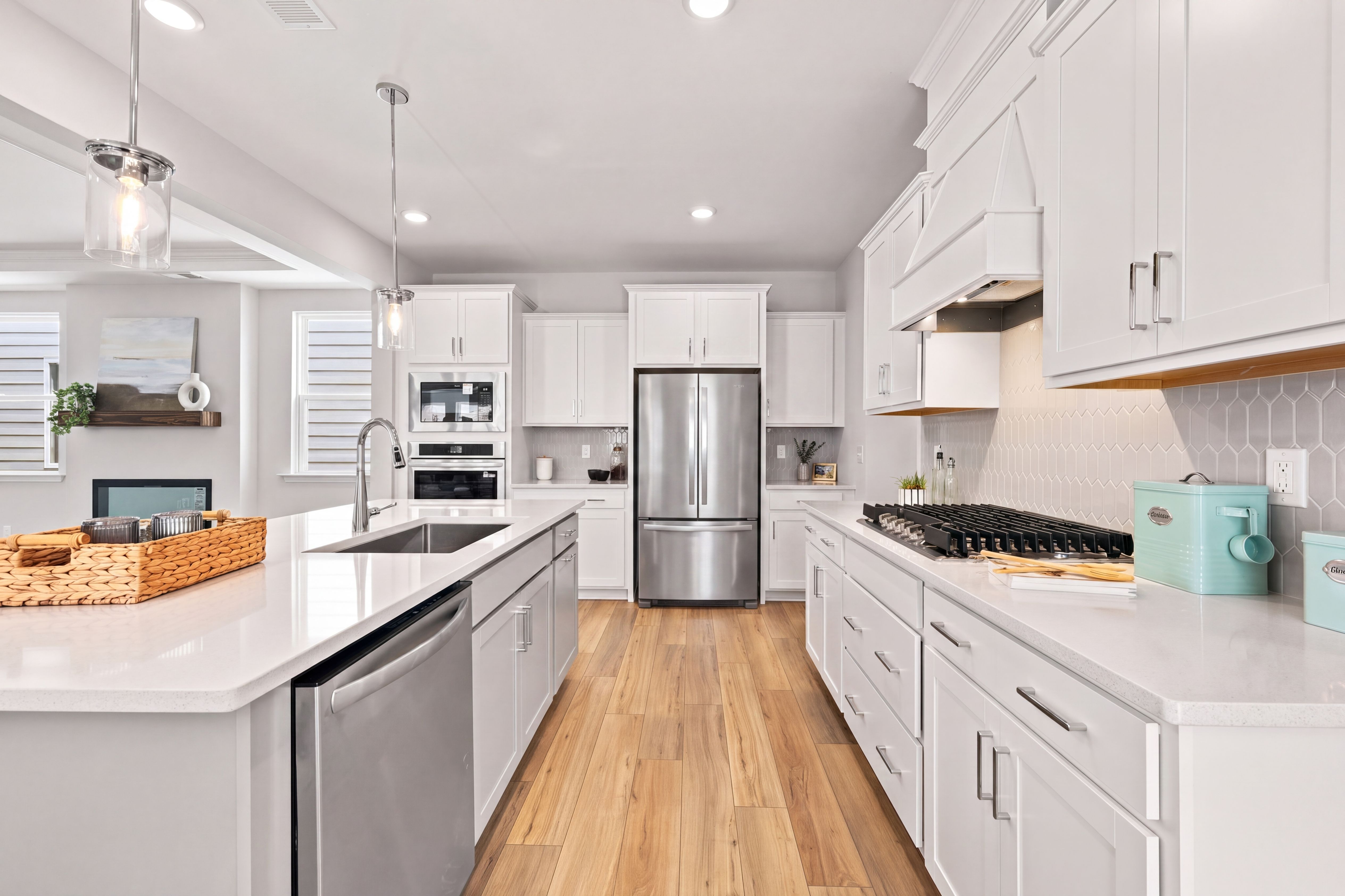 Modern gourmet kitchen in The Jordan home design featuring white cabinetry, stainless steel appliances, and a large island.
