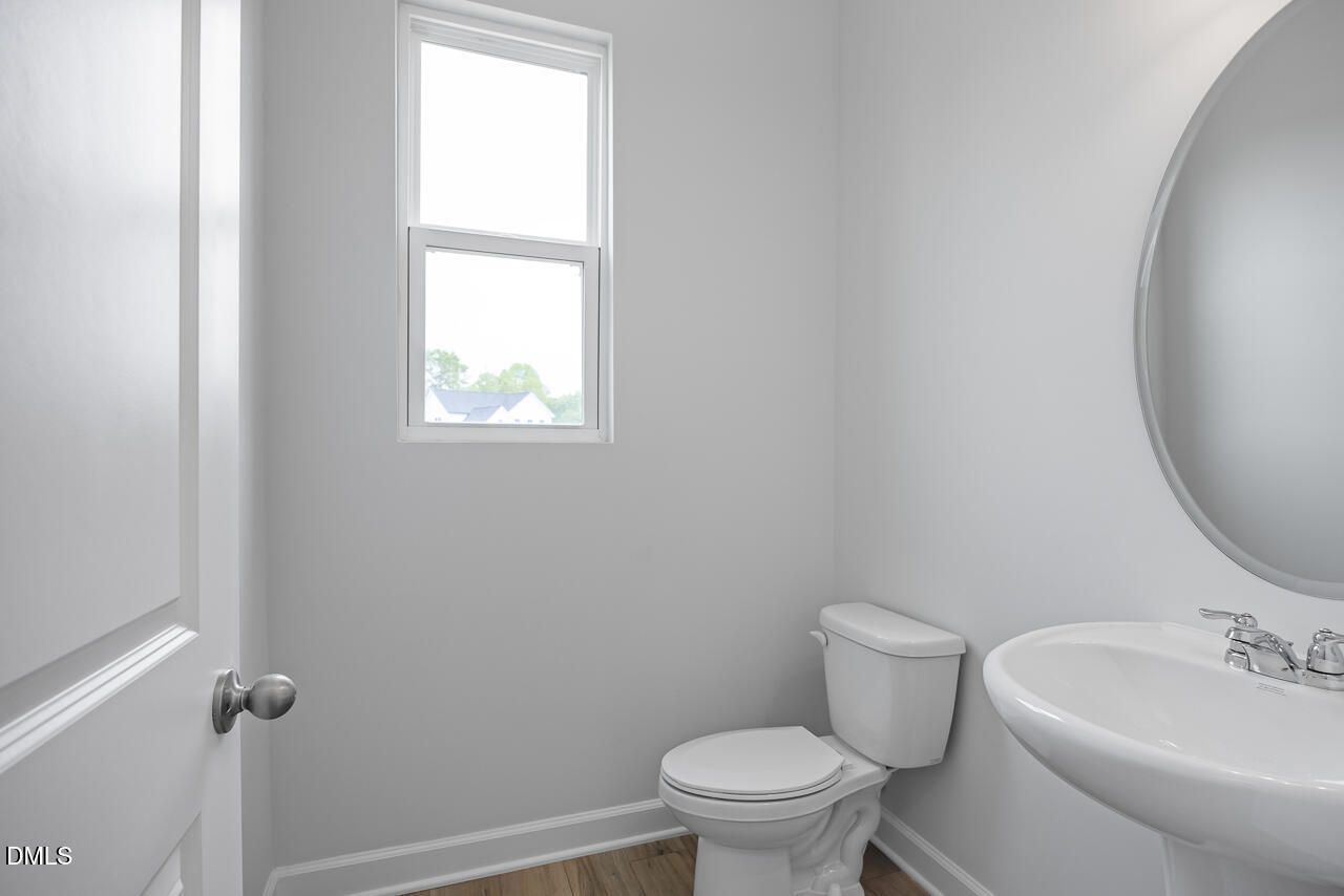 Modern half-bath with pedestal sink and round mirror in The Hickory II B floor plan at Woodland Crossing, Zebulon, NC.
