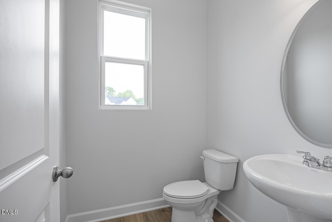 Modern half-bath with pedestal sink and round mirror in The Hickory II B floor plan at Woodland Crossing, Zebulon, NC.