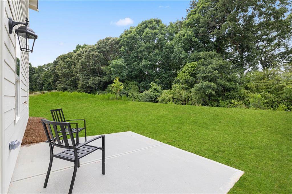 Concrete patio with outdoor seating overlooking a spacious private backyard in Cedar Farms, Winder, Georgia.