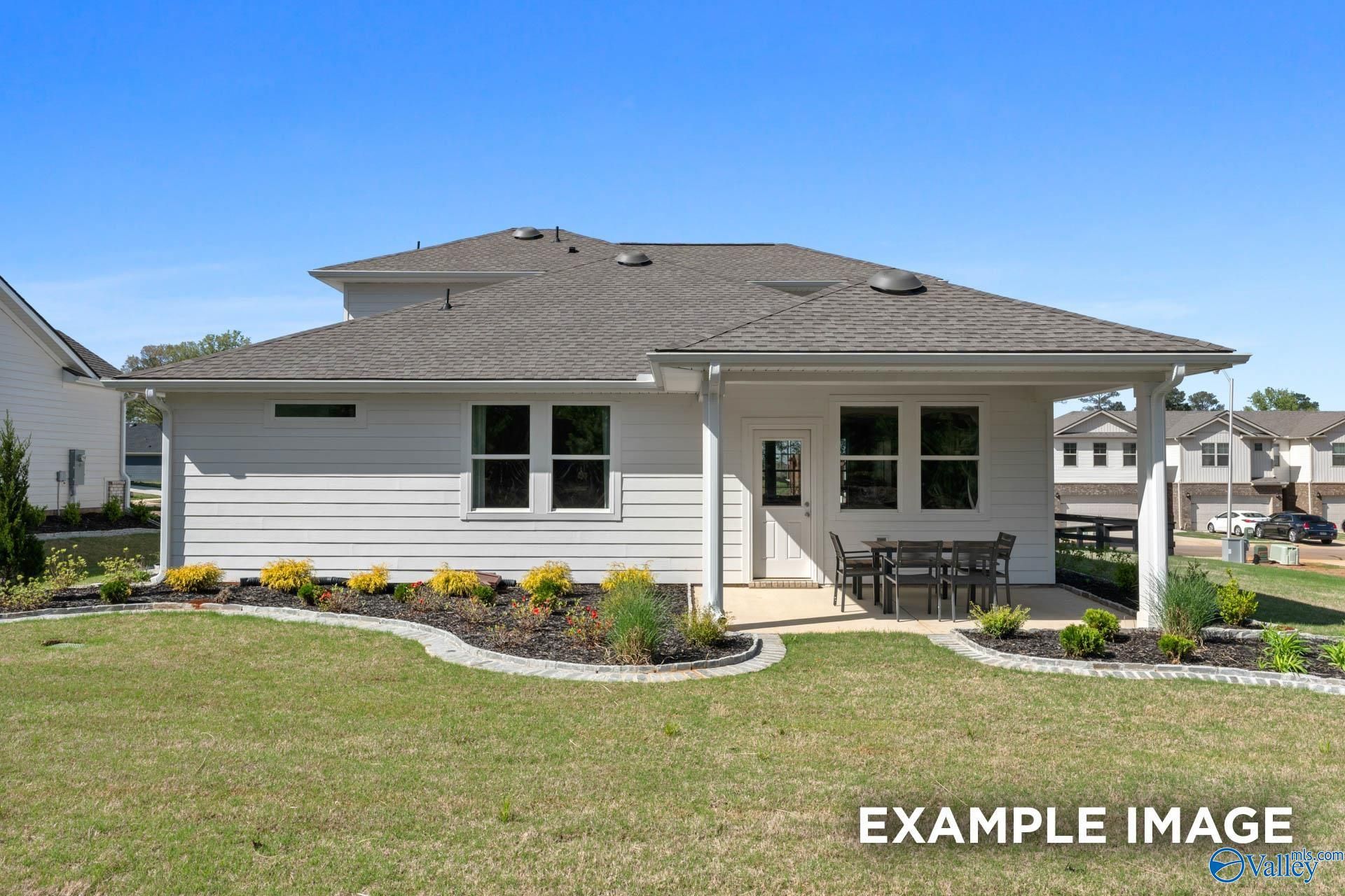 Two-story The Stella home exterior with covered porch, patio furniture, and landscaped yard in Evergreen Mill, Madison, Alabama