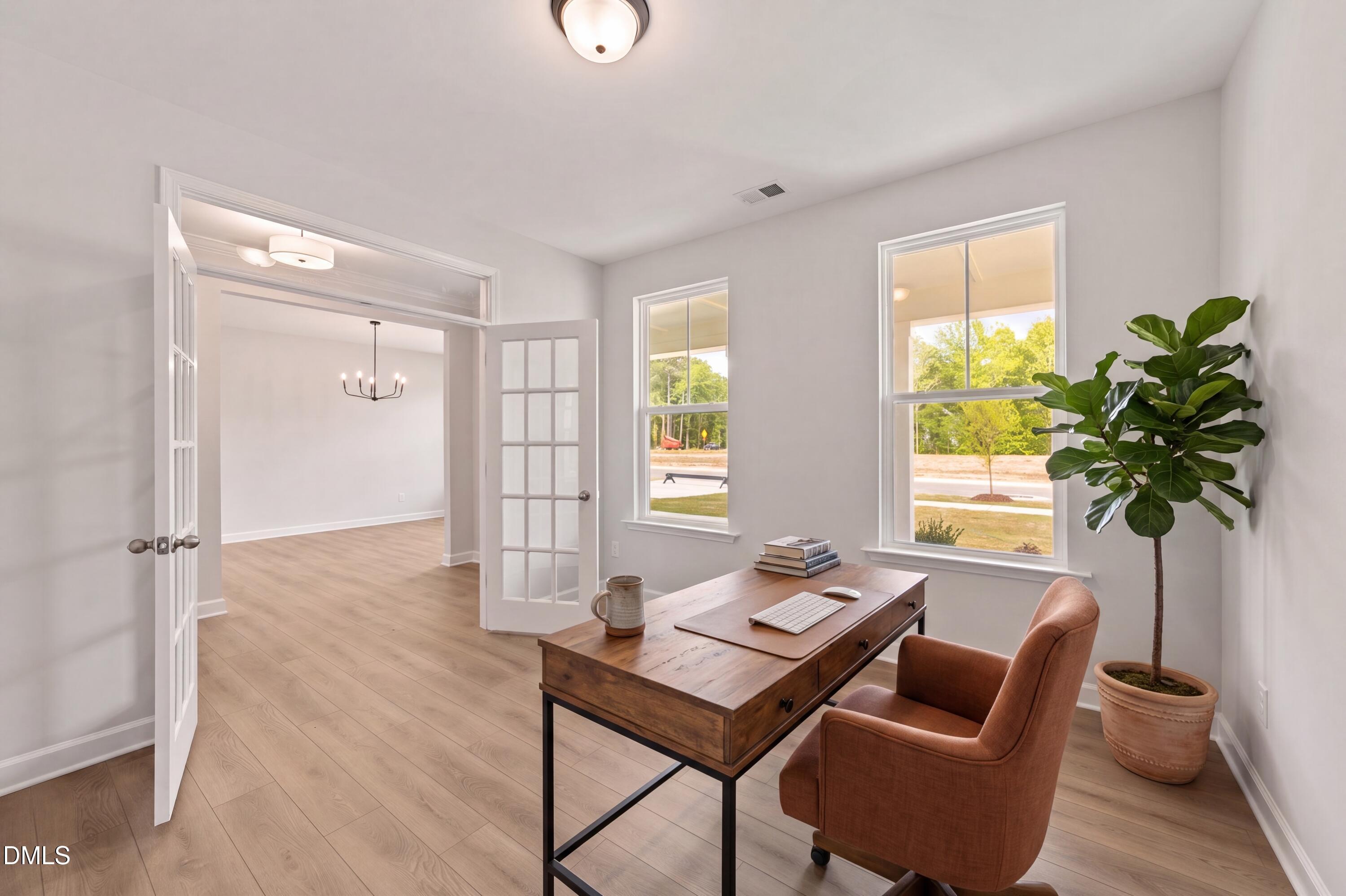 Bright home office with wooden desk, chair, and fiddle leaf fig in The Magnolia B floor plan at Wendell Ridge, NC.