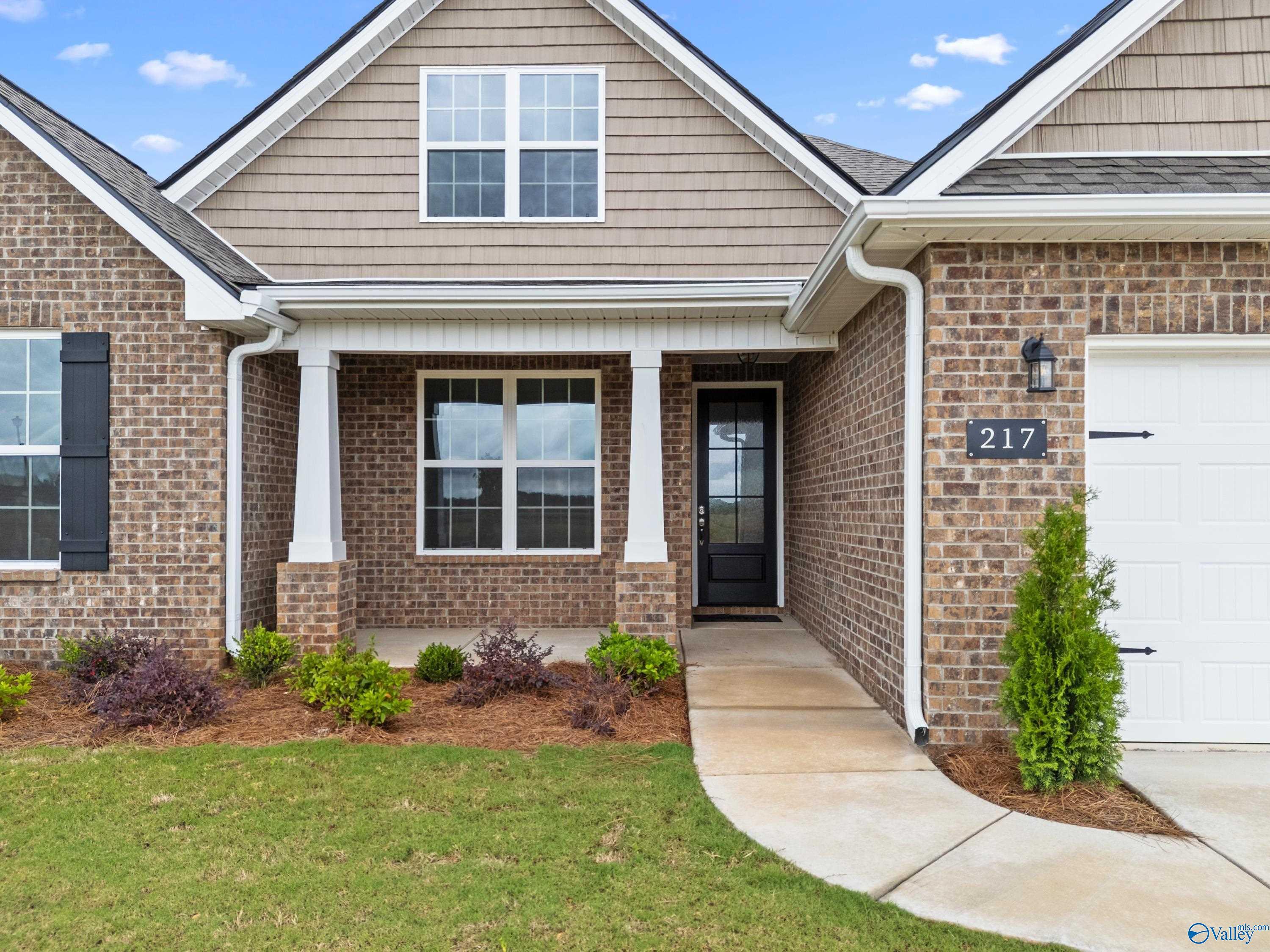 Modern 1-story Davidson Homes exterior with beige siding, brick base, 3-car garage, covered porch in Kendall Farms, Toney, Alabama