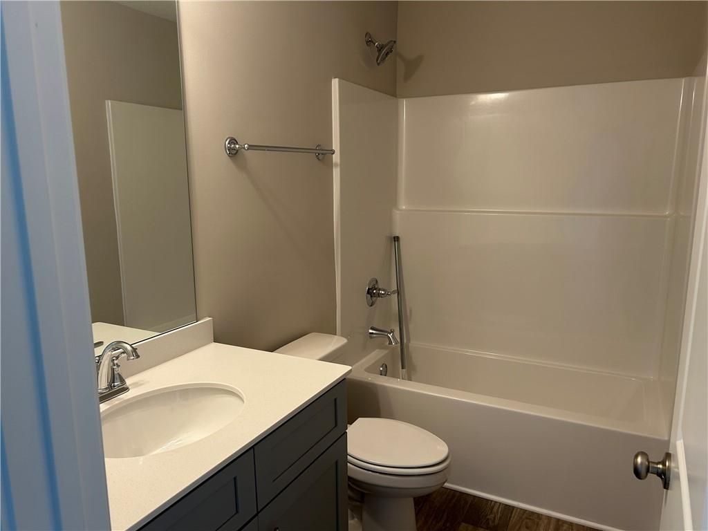Bright guest bathroom with white bathtub-shower combo, single vanity sink, and toilet in Davidson Homes The Washington, Phenix City, Alabama
