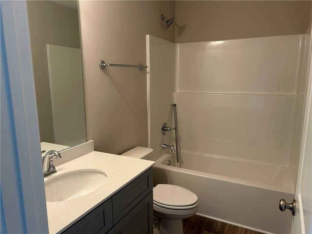 Bright guest bathroom with white bathtub-shower combo, single vanity sink, and toilet in Davidson Homes The Washington, Phenix City, Alabama