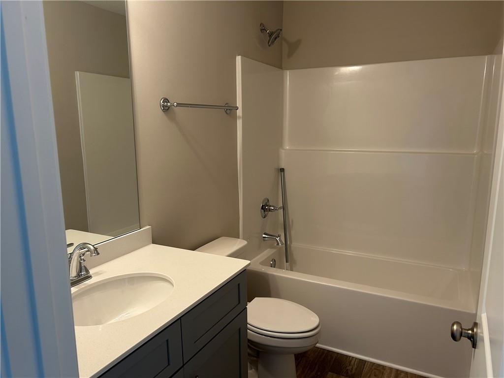 Bright guest bathroom with white bathtub-shower combo, single vanity sink, and toilet in Davidson Homes The Washington, Phenix City, Alabama