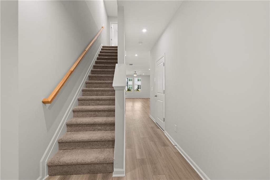 Bright entryway with carpeted staircase and wood-style flooring in The Monroe B floor plan at Stegall Village, Emerson.