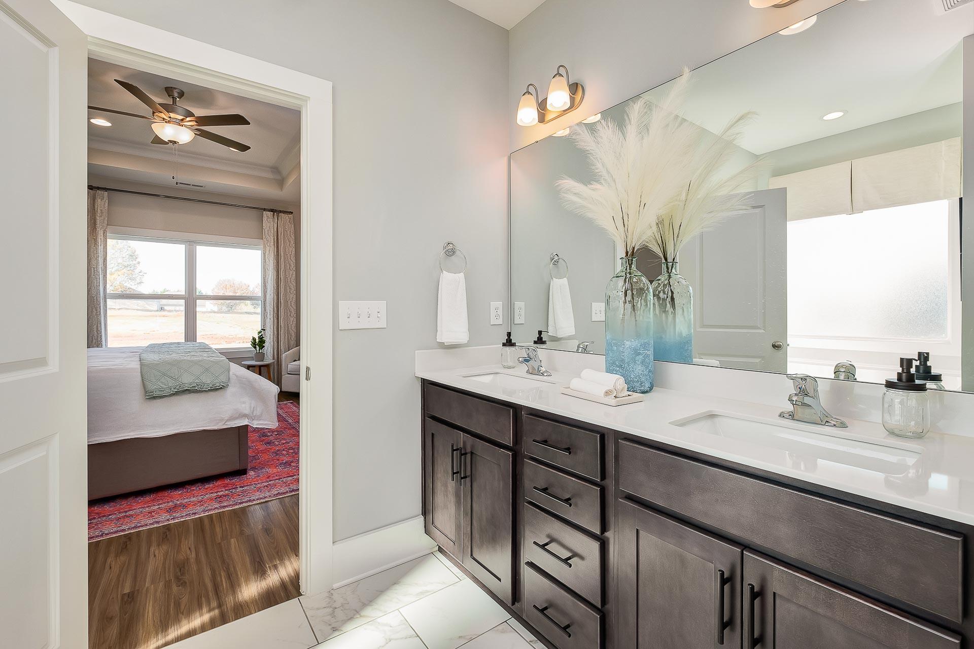 Spacious master bathroom with double vanity, large mirror, and open view to bedroom at Newby Chapel in Athens, Alabama