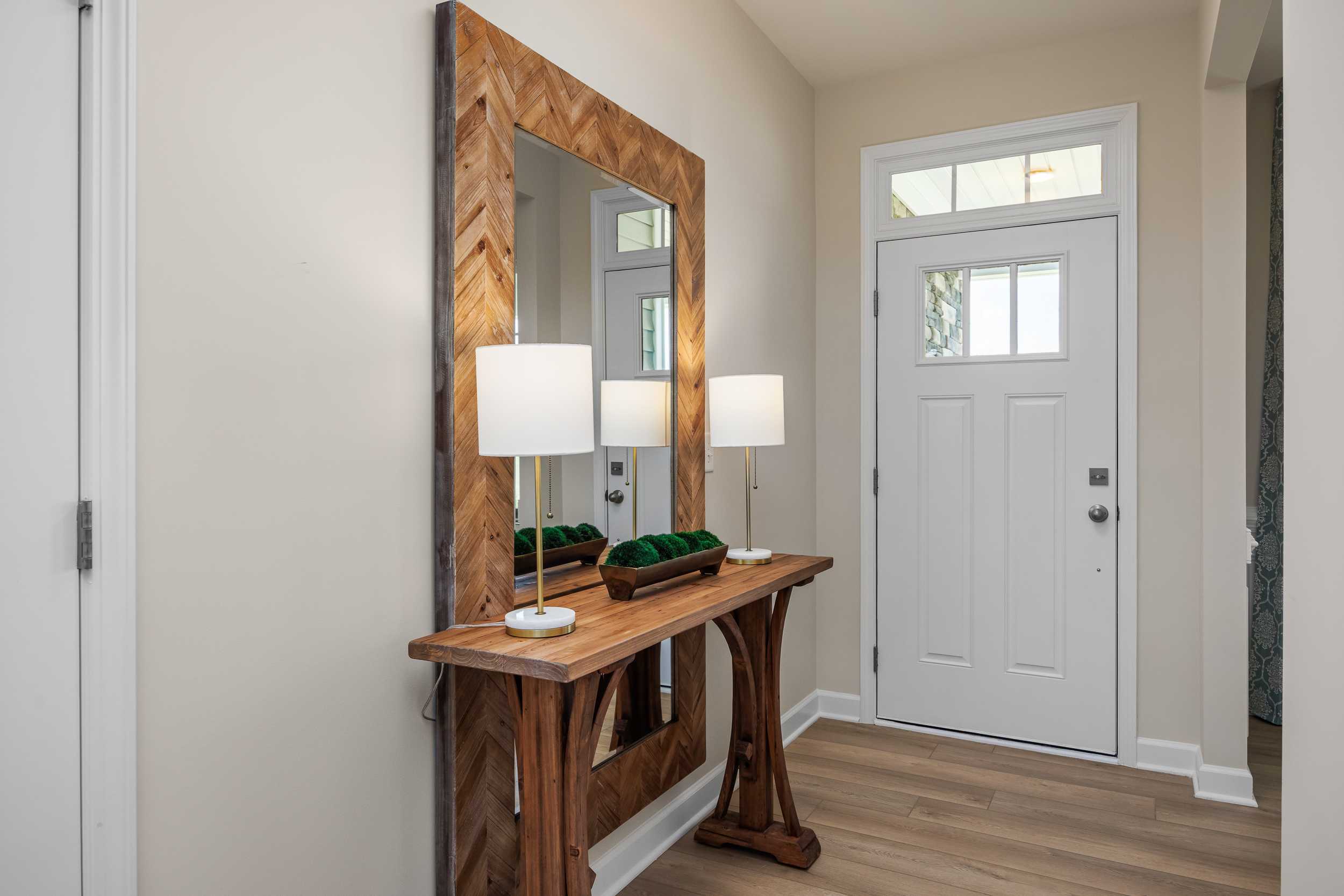 Elegant entryway at Retreat at North Main in Lillington NC with large wooden mirror console table white lamps and front door