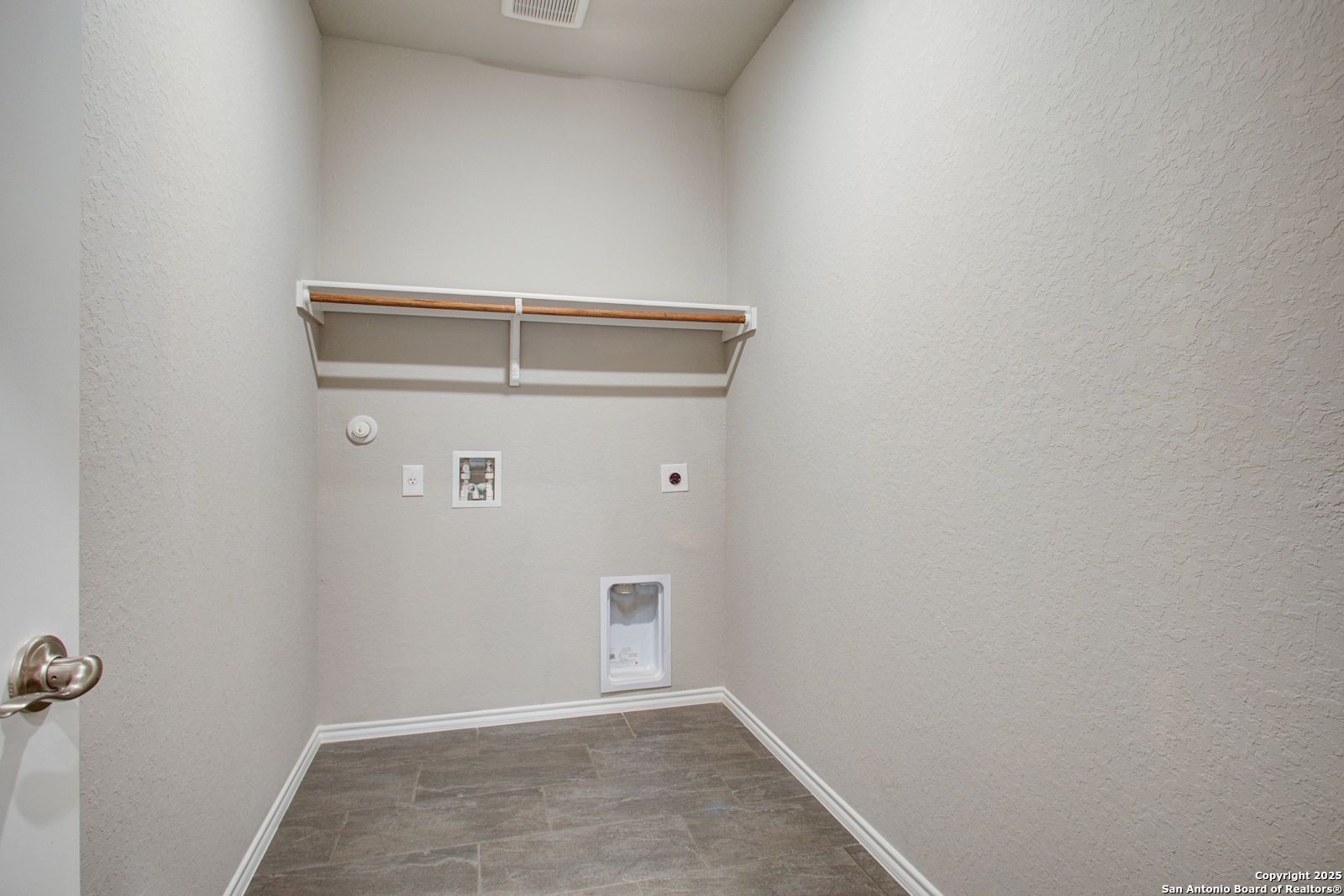 Spacious laundry room with built-in wooden shelves, washer/dryer hookups, pet door in 4-bedroom Davidson Homes Douglas G, San Antonio, Texas