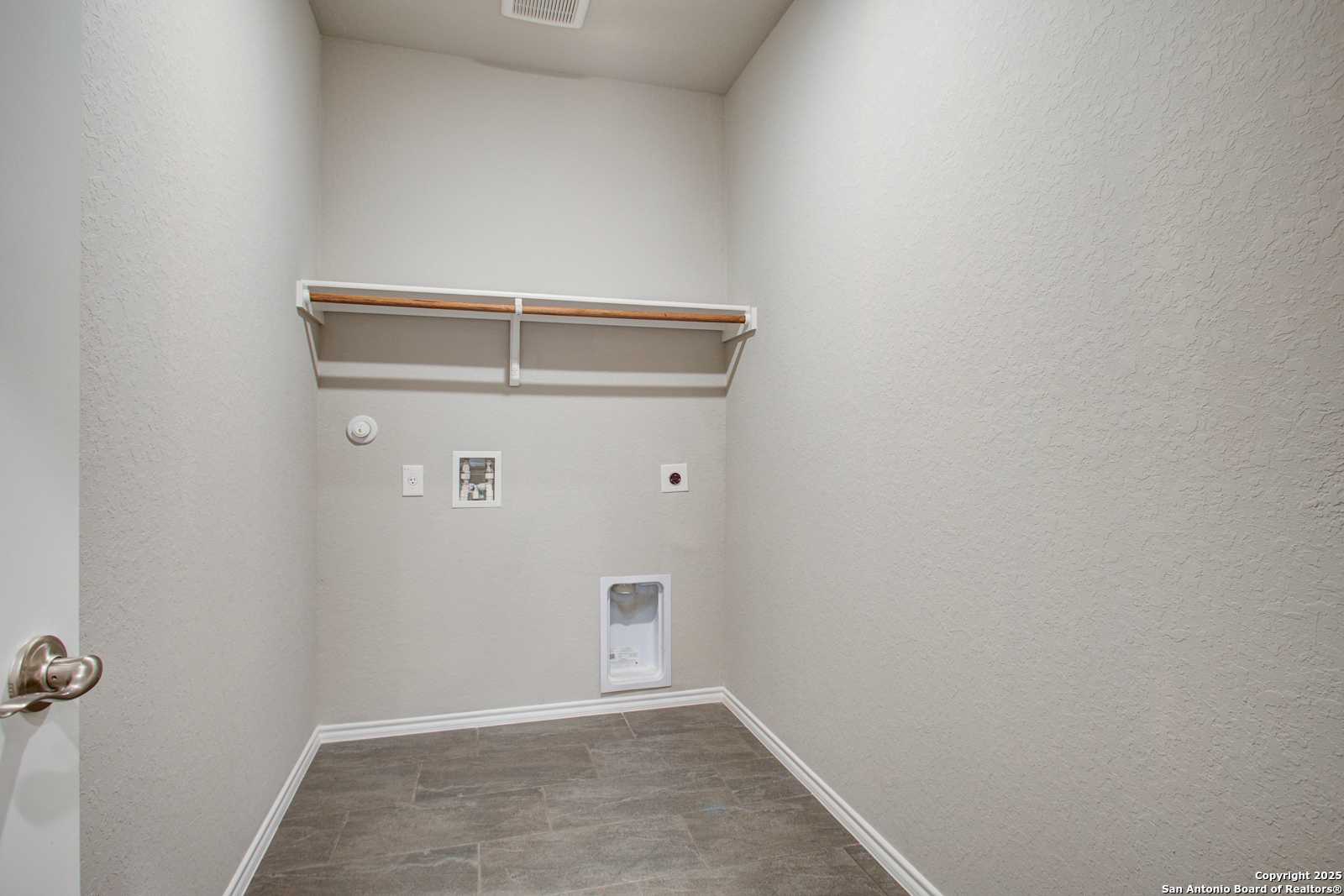 Spacious laundry room with built-in wooden shelves, washer/dryer hookups, pet door in 4-bedroom Davidson Homes Douglas G, San Antonio, Texas