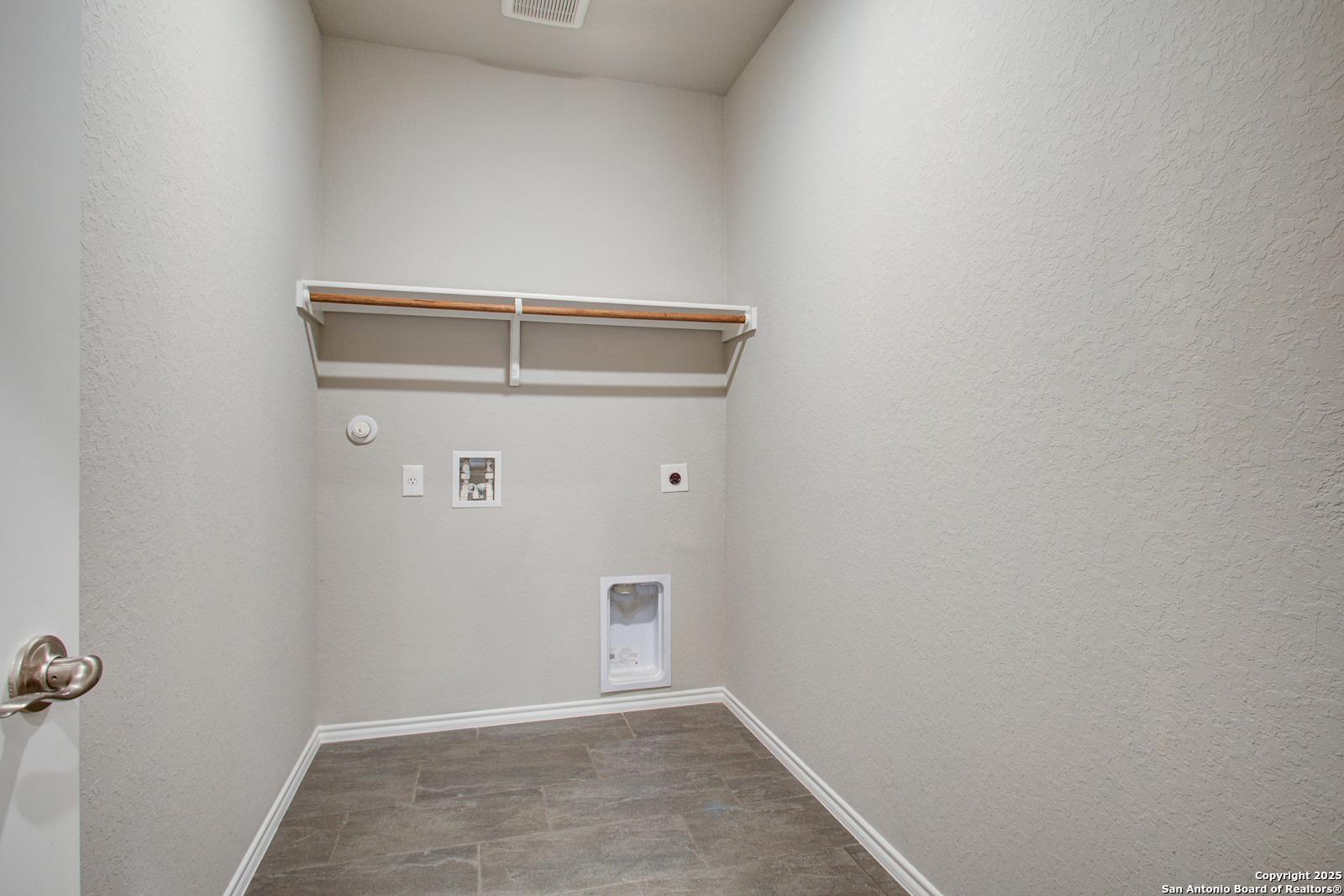 Spacious laundry room with built-in wooden shelves, washer/dryer hookups, pet door in 4-bedroom Davidson Homes Douglas G, San Antonio, Texas