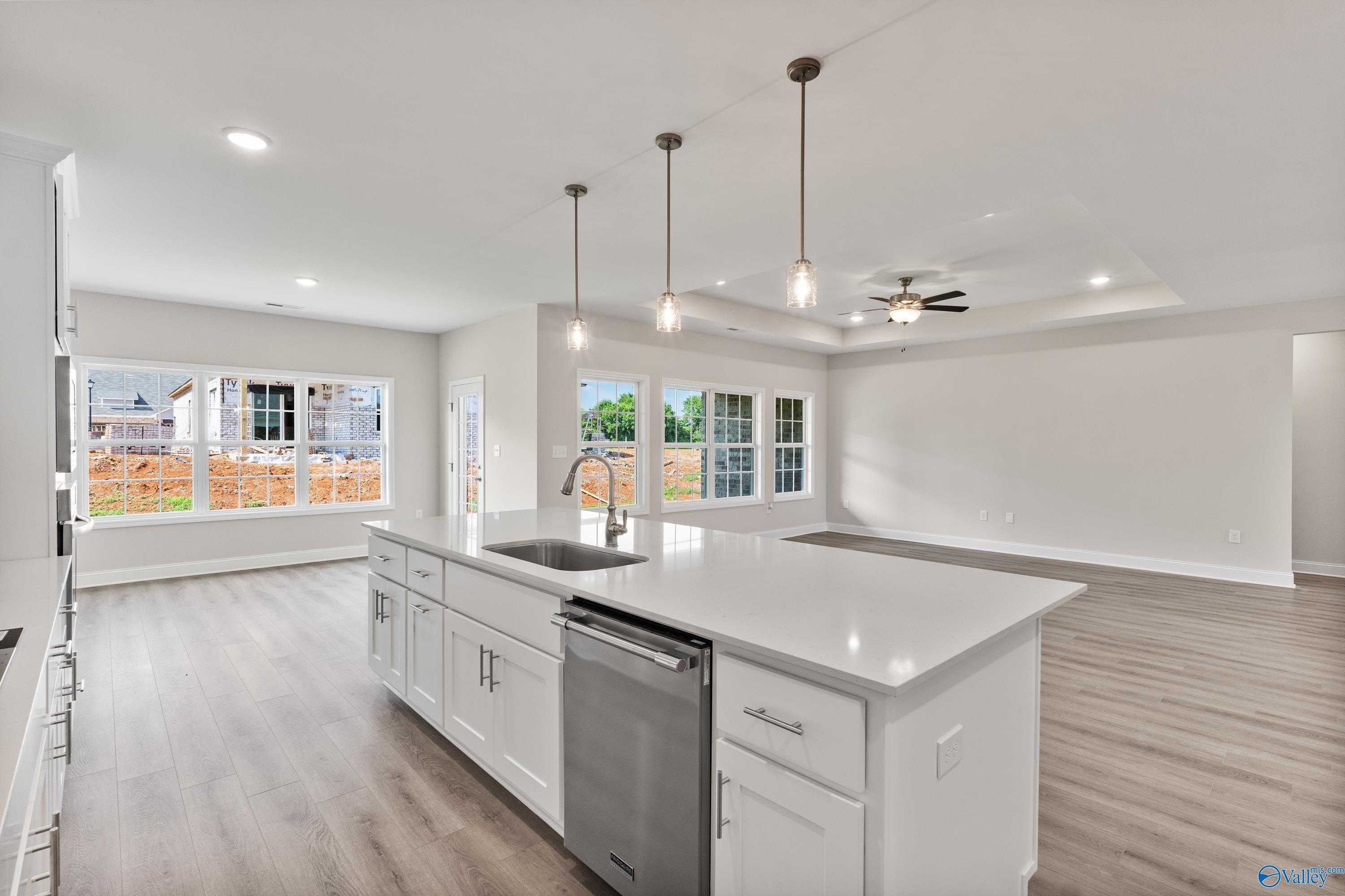 Bright open-concept kitchen with white quartz island, stainless sink, pendant lights, and large windows to backyard in Davidson Homes The Finleigh, Toney, Alabama
