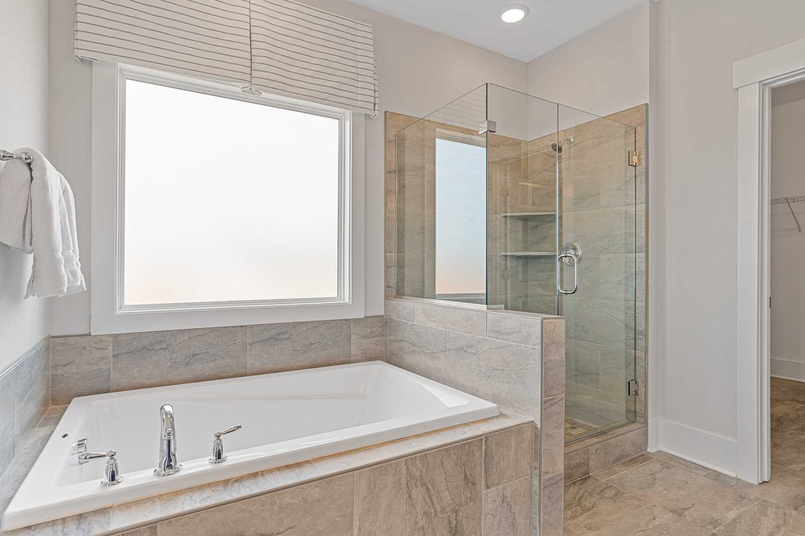 Master bathroom tub and shower with frosted glass window over tub