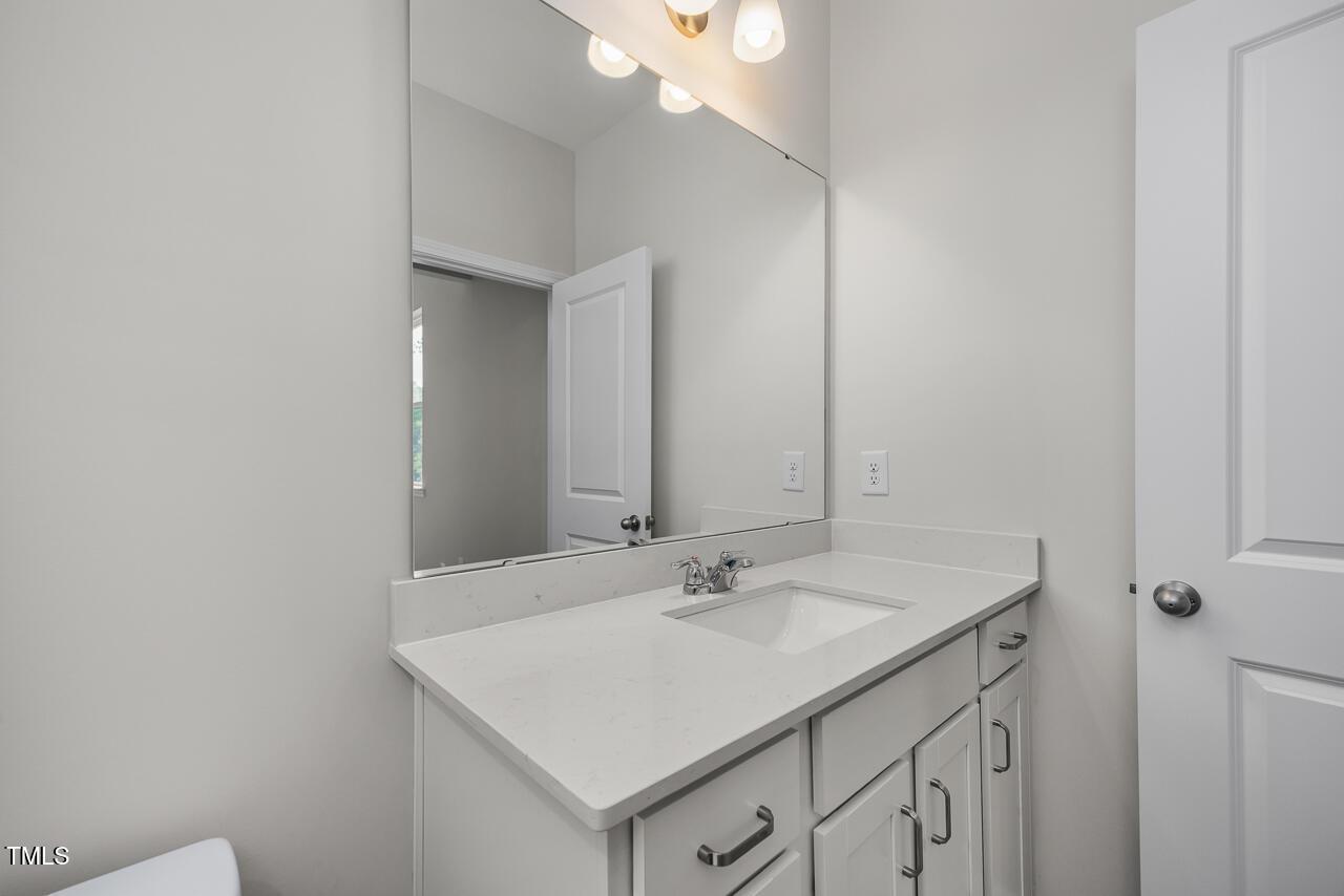 Elegant bathroom vanity with white shaker cabinets, quartz countertop, and large mirror in Davidson Homes The Aspen B, Wake Forest, NC