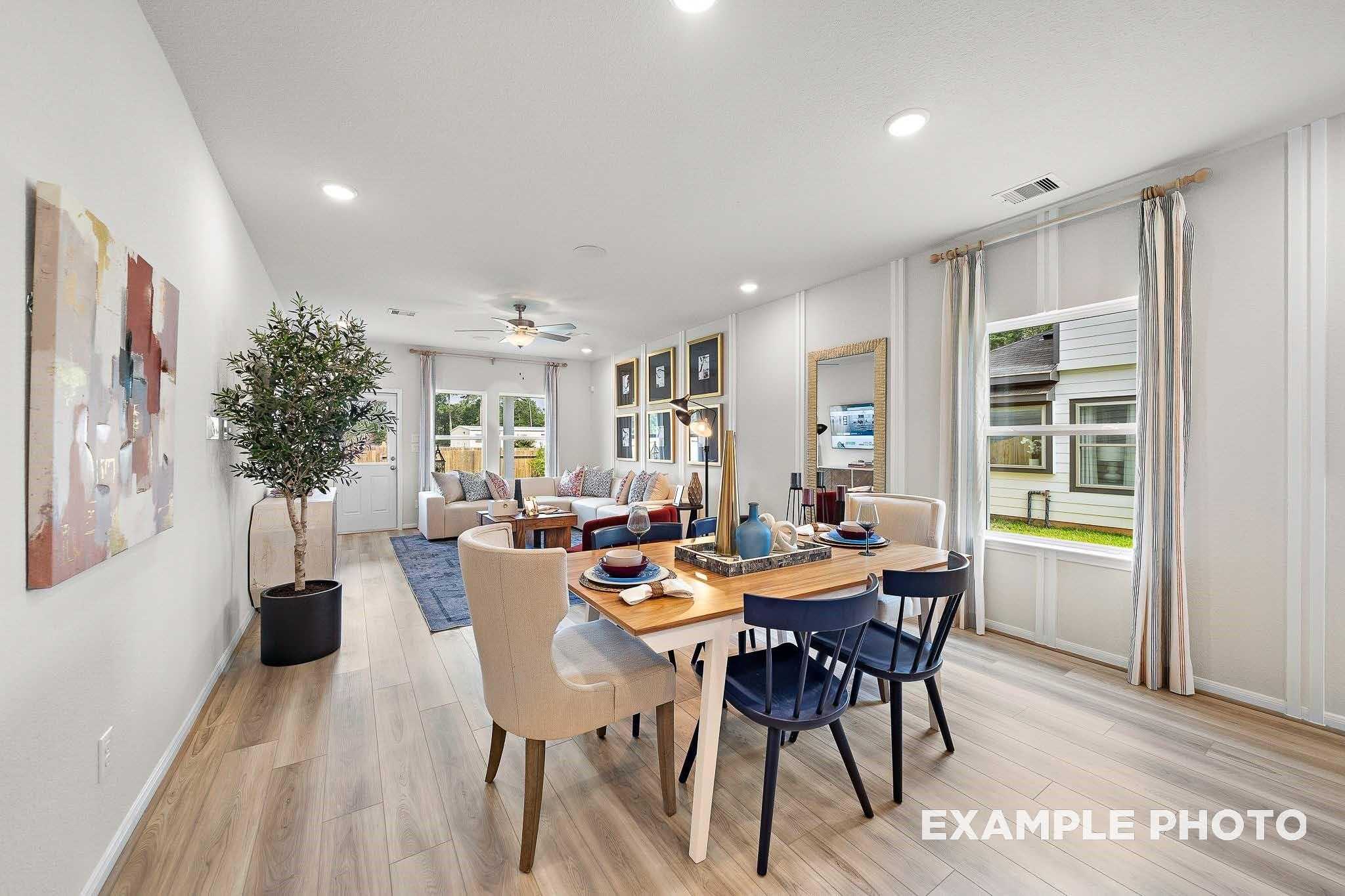 Spacious open dining and living room with wood table, mixed chairs, sofa, large windows in Davidson Homes San Marcos E, Conroe Texas