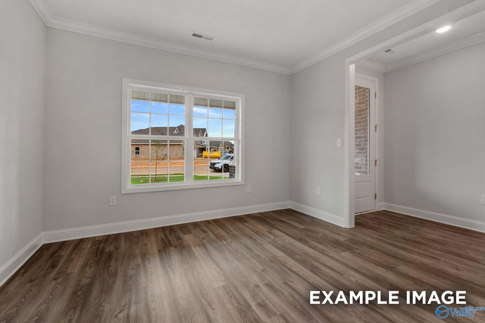 Bright secondary bedroom with gray walls, hardwood floors, and large window view in The Shelby C by Davidson Homes, Arab, Alabama