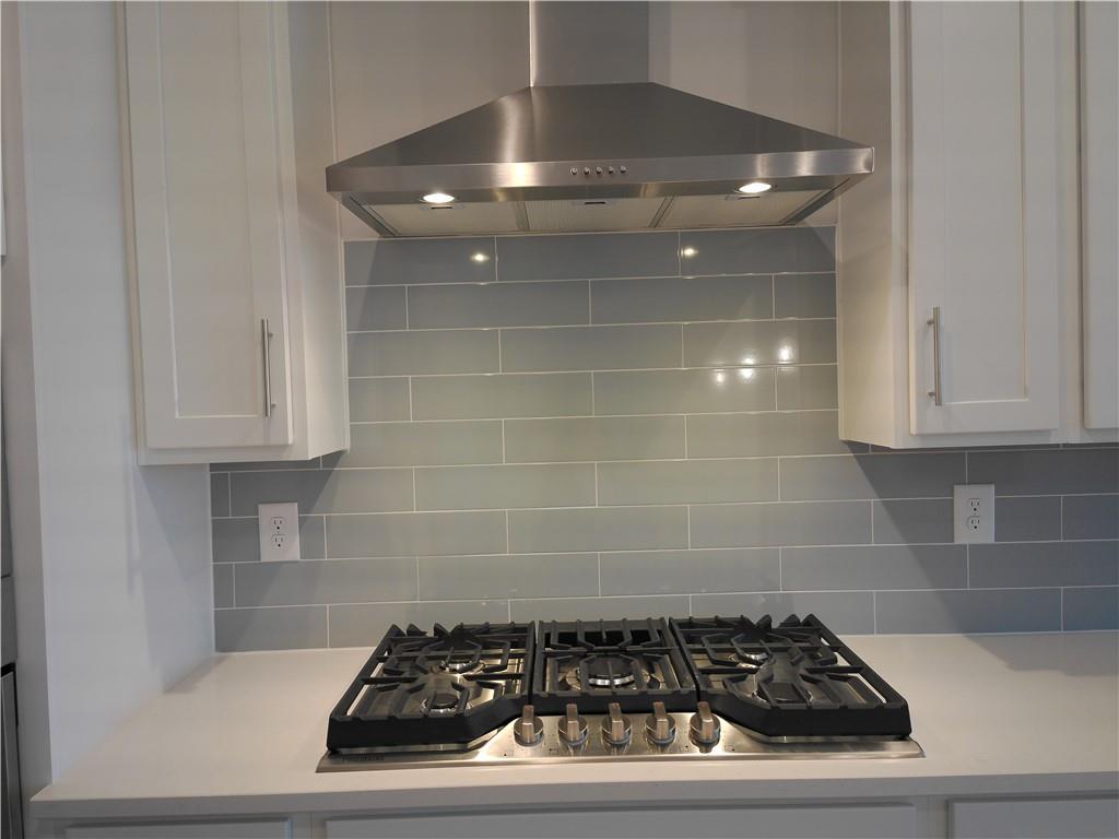 Modern kitchen with stainless steel range hood, gas cooktop, white shaker cabinets, subway tile backsplash in Davidson Homes The Marion C, Winder, GA