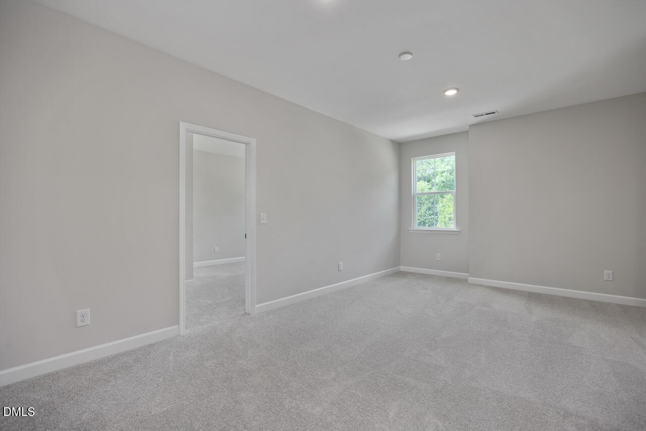 Bright, spacious bedroom with neutral carpet in The Ashport L floor plan at Sage on North Main, Wake Forest, NC.