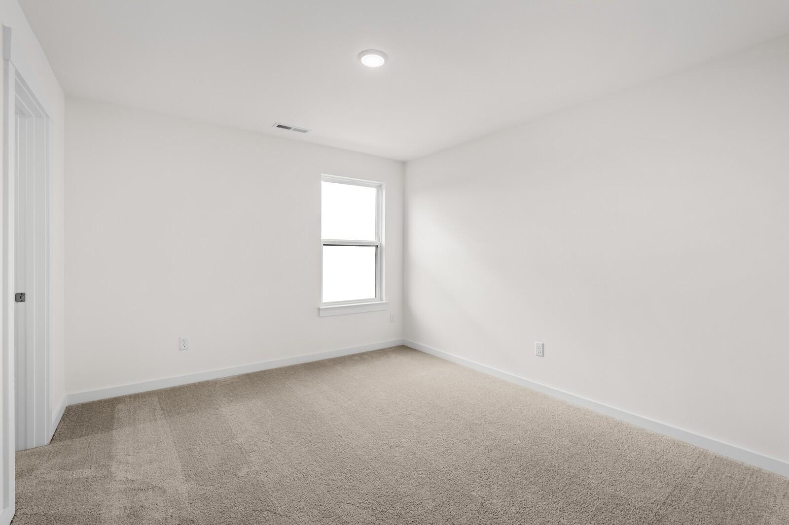 Bright, carpeted bedroom with neutral walls in The Henry C floor plan at Benders Cove, Mt. Juliet, Tennessee.