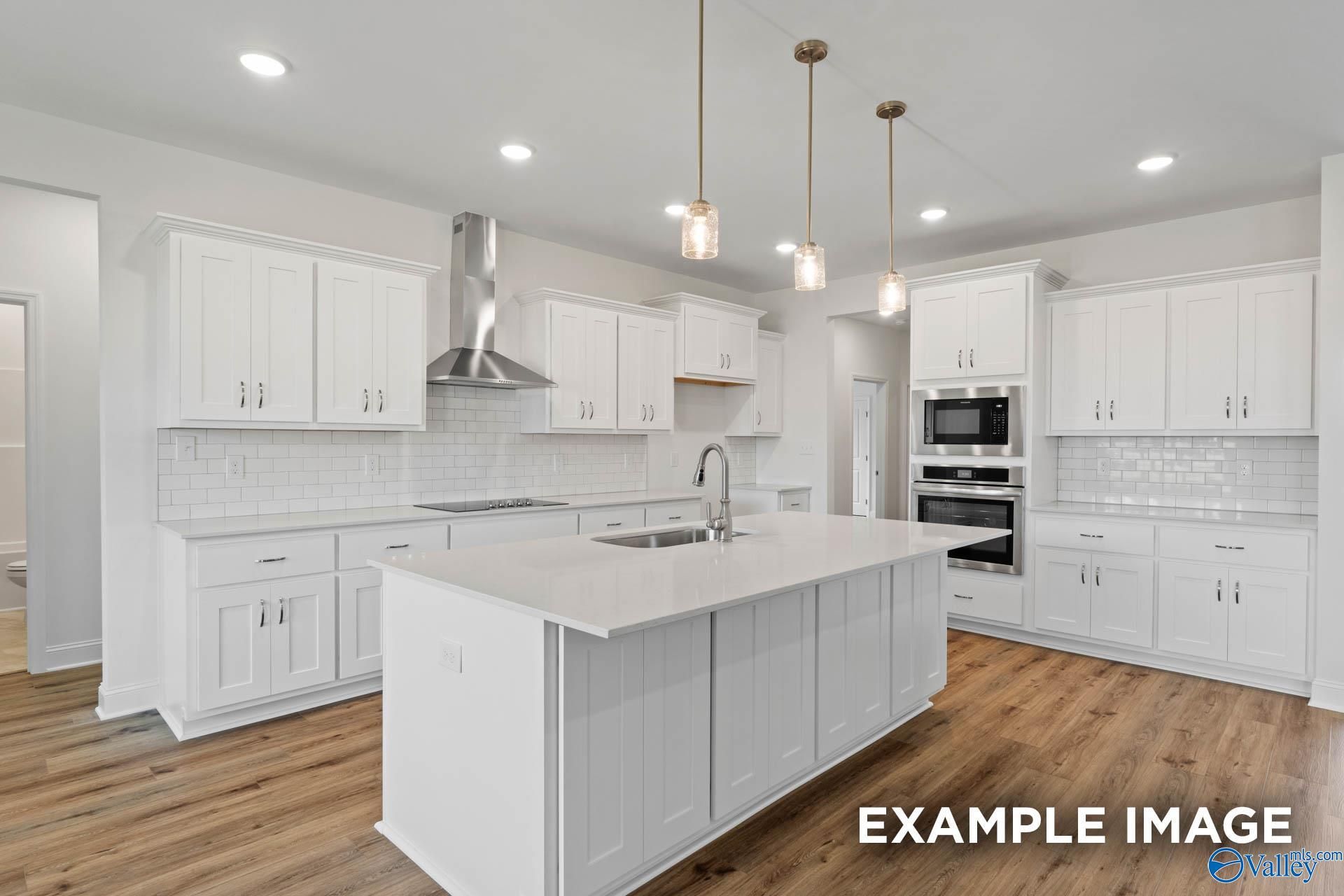 Bright white kitchen with large island, subway tile backsplash, stainless appliances in Davidson Homes The Oxford, Huntsville AL