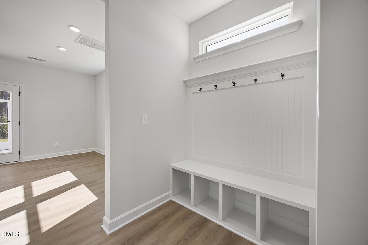 Mudroom with built-in bench storage, coat hooks, and beadboard accent wall in Davidson Homes The Preston C, Wendell Ridge, NC