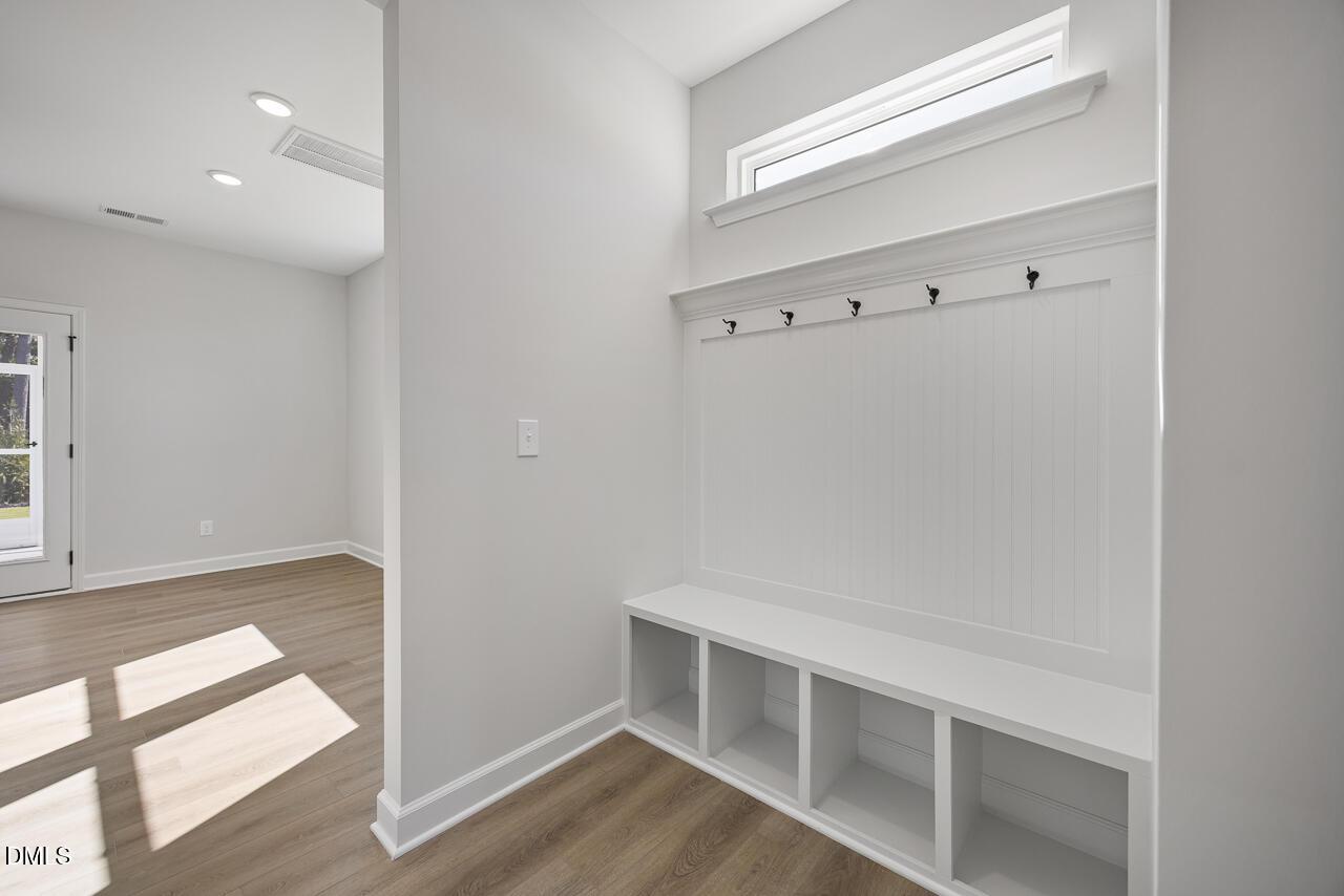 Mudroom with built-in bench storage, coat hooks, and beadboard accent wall in Davidson Homes The Preston C, Wendell Ridge, NC