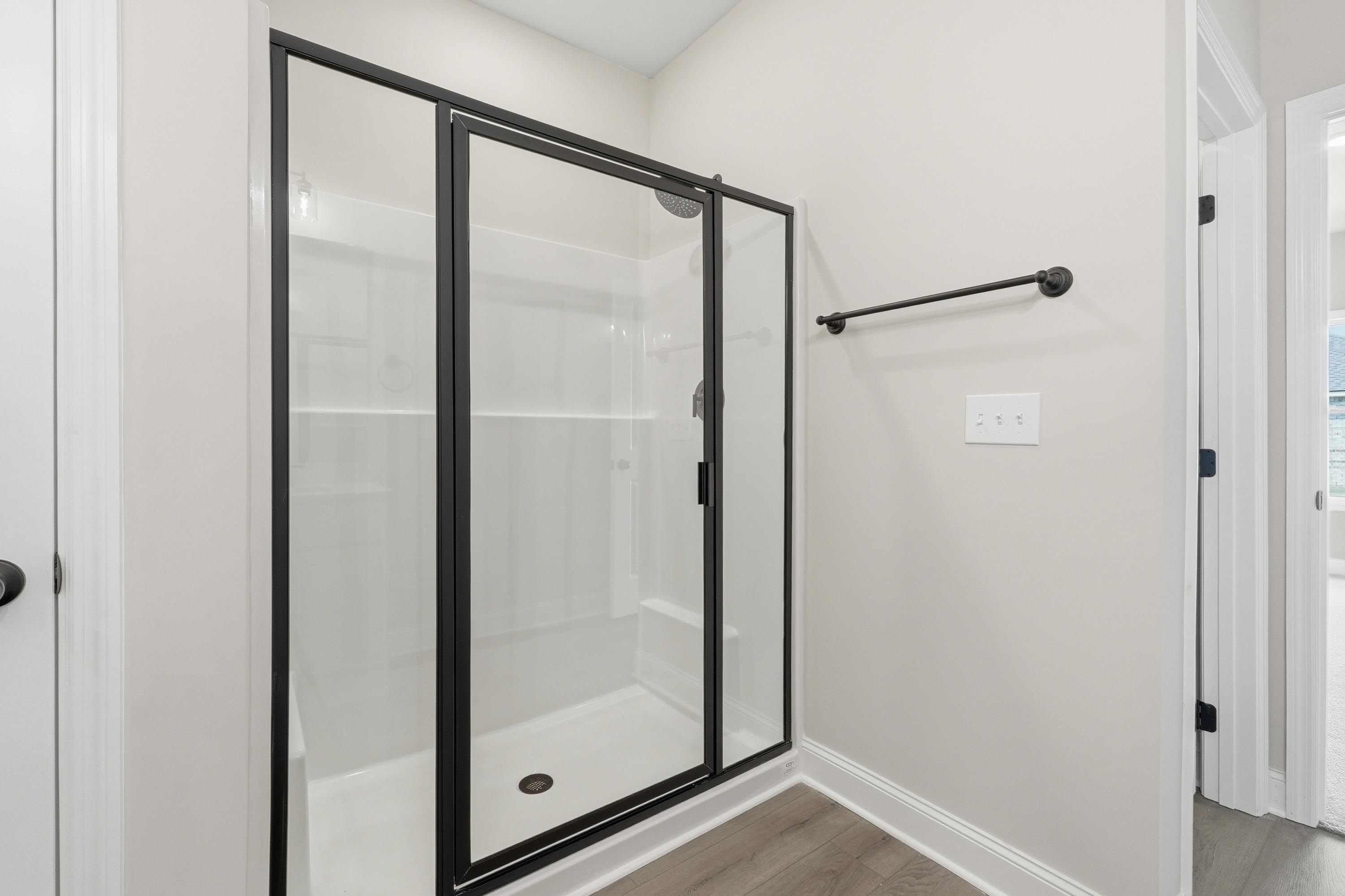 Modern walk-in shower with black frame in the master suite of The Glen A home design in Josephine, Texas.