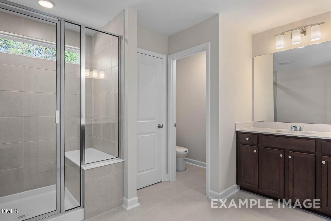 Modern master bathroom with frameless glass shower, dark wood vanity, and subway tile in Davidson Homes The Graham plan, Fuquay-Varina, NC