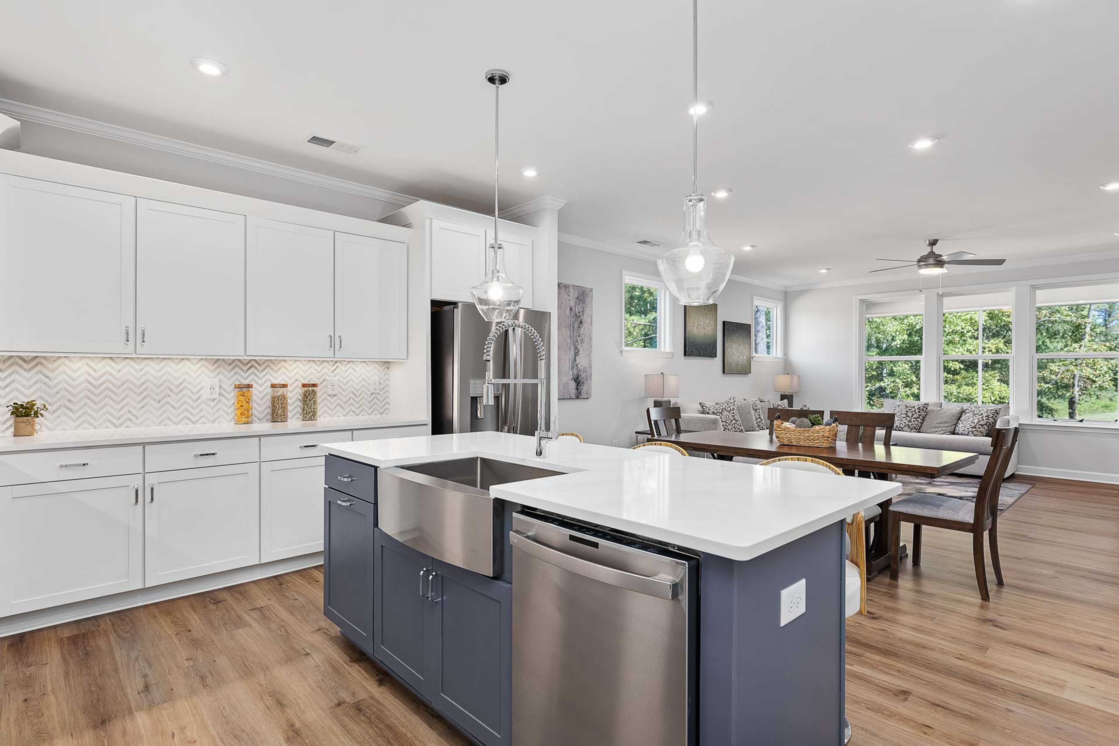 Spacious open-concept kitchen and dining in Glenmere Knightdale NC by Davidson Homes with white cabinets navy island hardwood floors