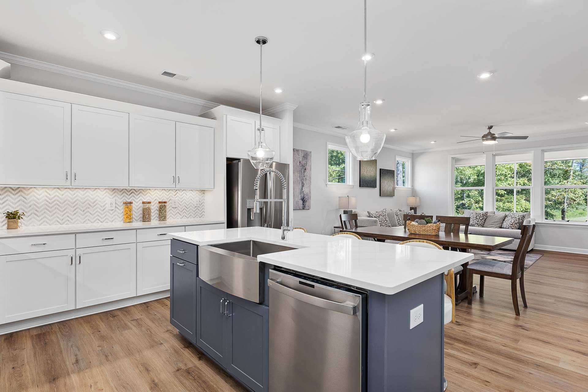 Spacious open-concept kitchen and dining in Glenmere Knightdale NC by Davidson Homes with white cabinets navy island hardwood floors