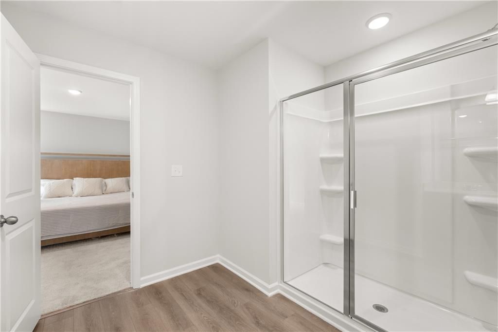 Modern bathroom with glass-enclosed shower and view into bedroom in The Sinclair B floor plan at Cedar Farms, Winder, GA.