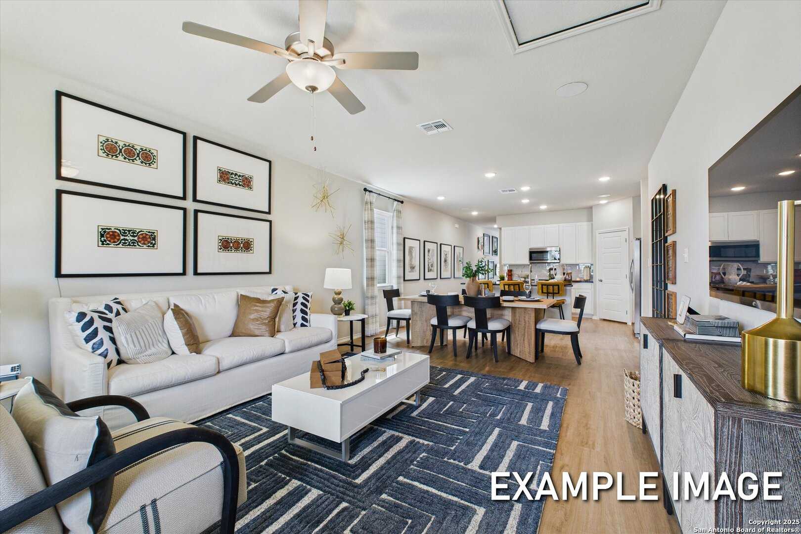 Spacious open-concept living room with white sofa, dining table, and kitchen island in Davidson Homes The Sabine C, San Antonio