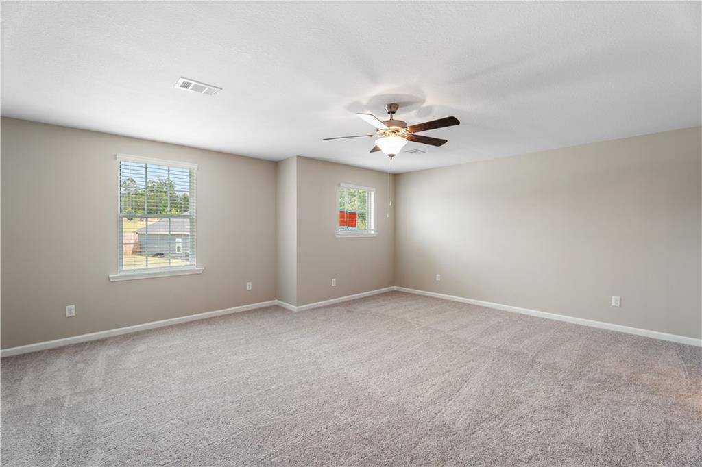 Bright secondary bedroom with ceiling fan, beige carpet, and window views in Davidson Homes The Bartlett, Phenix City, Alabama